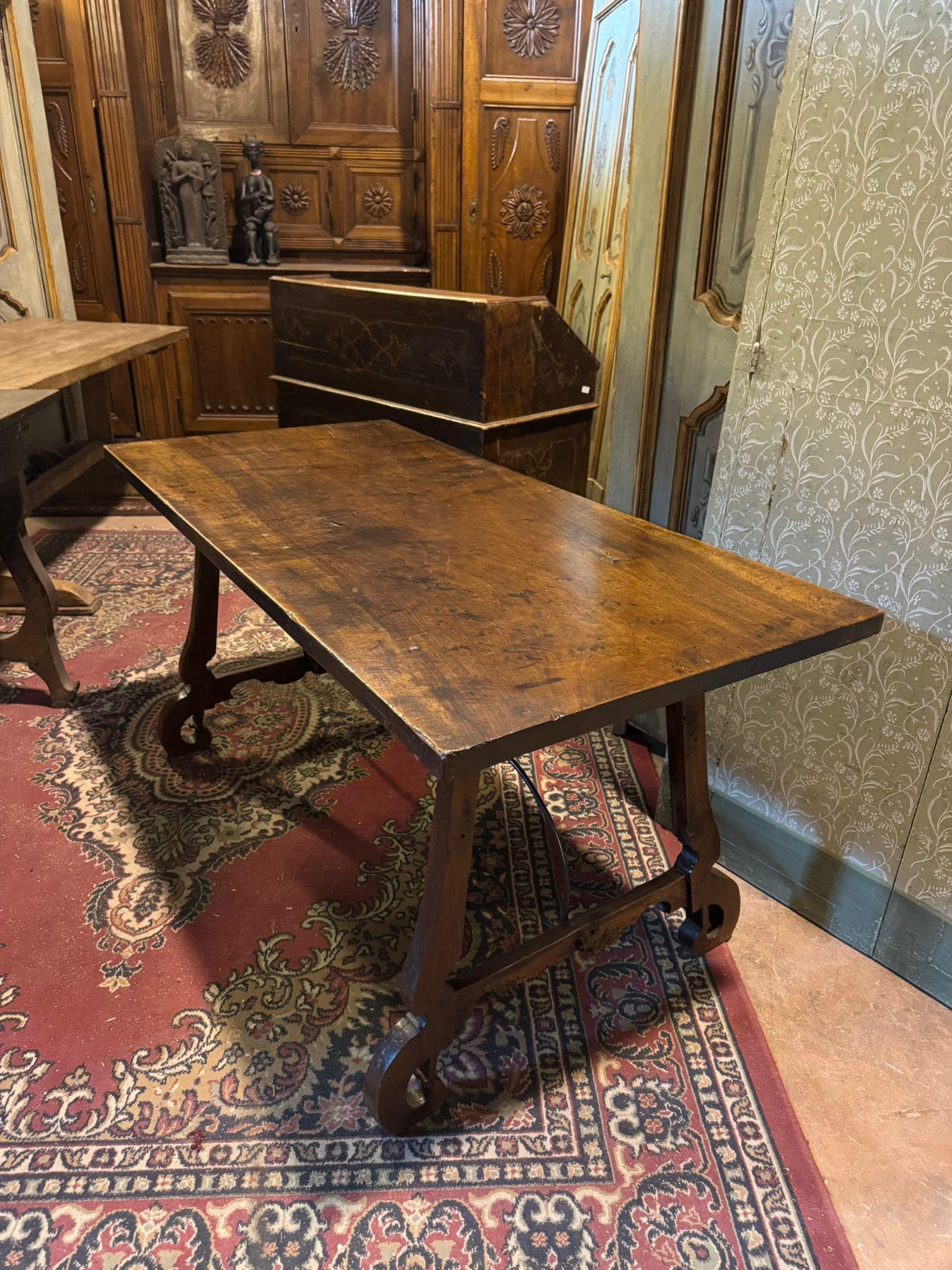 Mesa de refectorio antigua, mesa de comedor de preciosa madera maciza de nogal con patas en forma de lira unidas por un travesaño de hierro forjado típico del estilo y la época, completado con pies rizados.
Original del siglo XVIII, procedente de