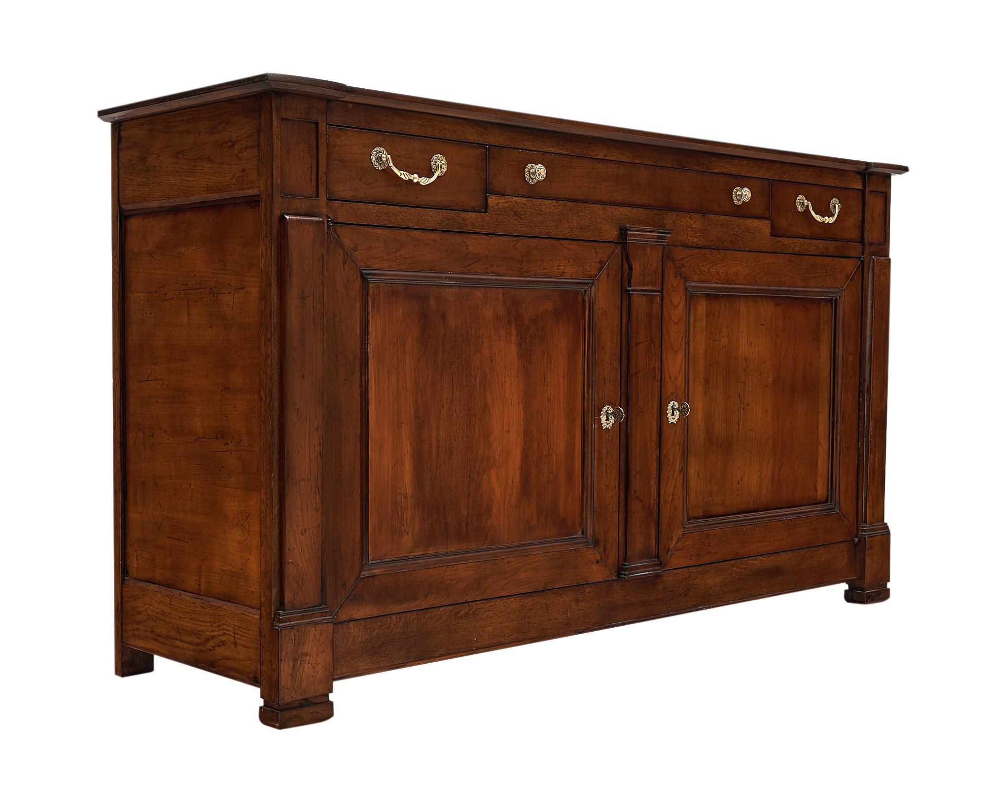 Buffet, French, made of solid walnut from the Rhone Valley in the Restoration style. This piece has two doors and three dovetailed drawers, all with bronze hardware. This elegant neoclassical provincial sideboard is finished in a lustrous bee wax