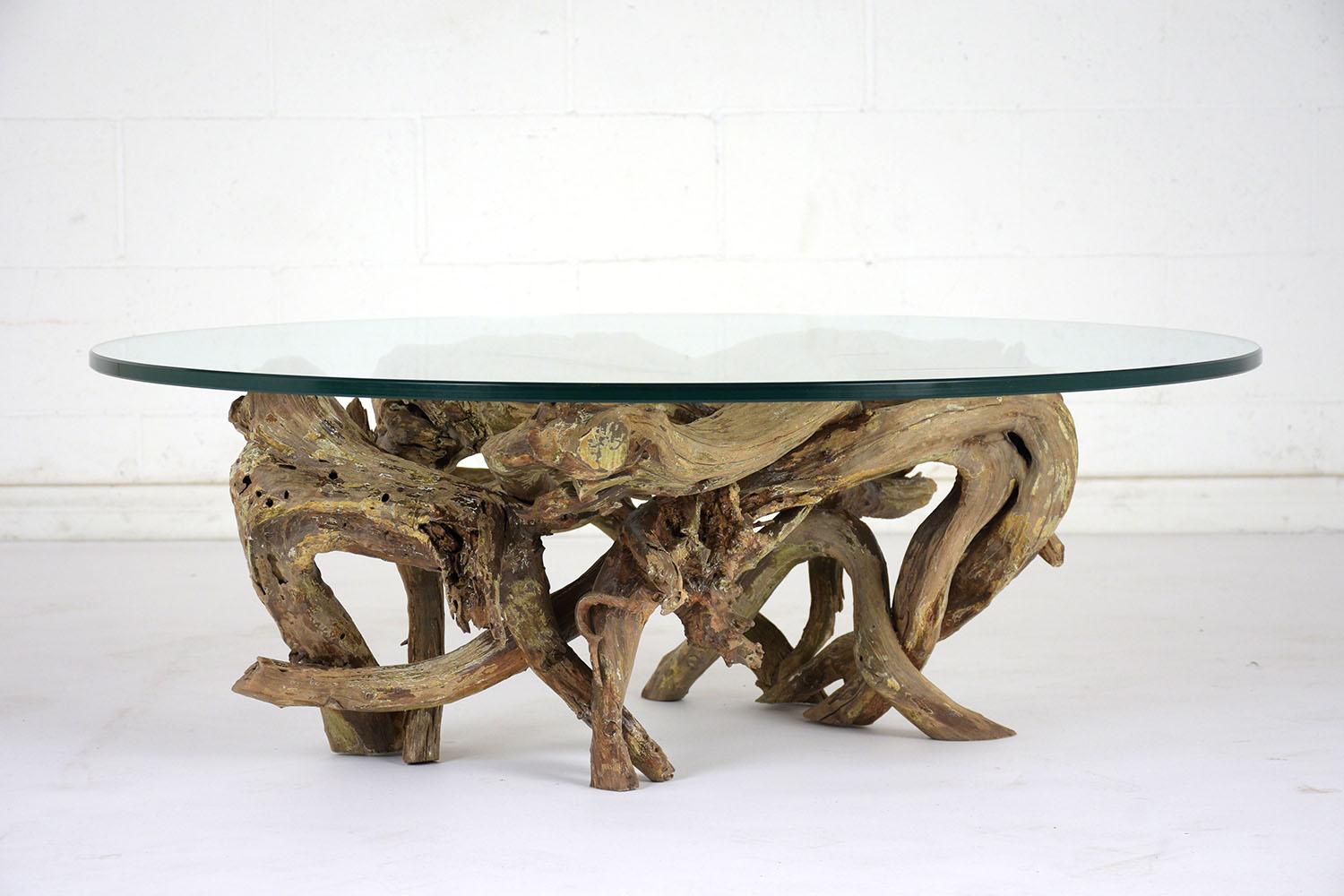 This 1950s free-form root coffee table has an organic elegance in the overlapping curves of the base. The root base is finished in a natural color with traces of age throughout. The tabletop is a 3/8 inch thick glass with a pencil polish finish in