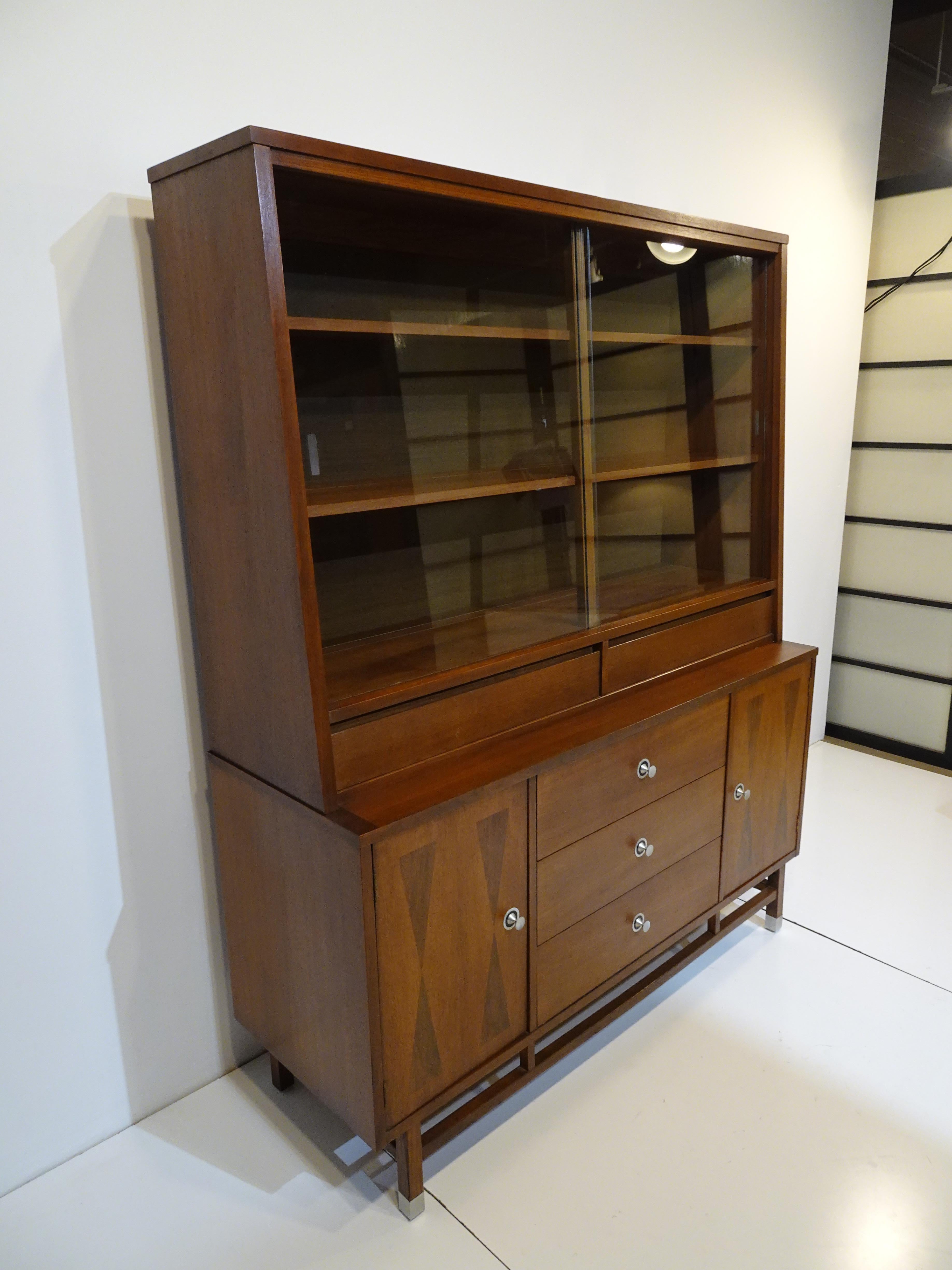 A well crafted dark walnut hutch / bookcase / china cabinet with rosewood detailed door fronts and turned aluminum pulls. The upper case has two non adjustable shelves and sliding glass doors the lower cabinet has three drawers and two door to each