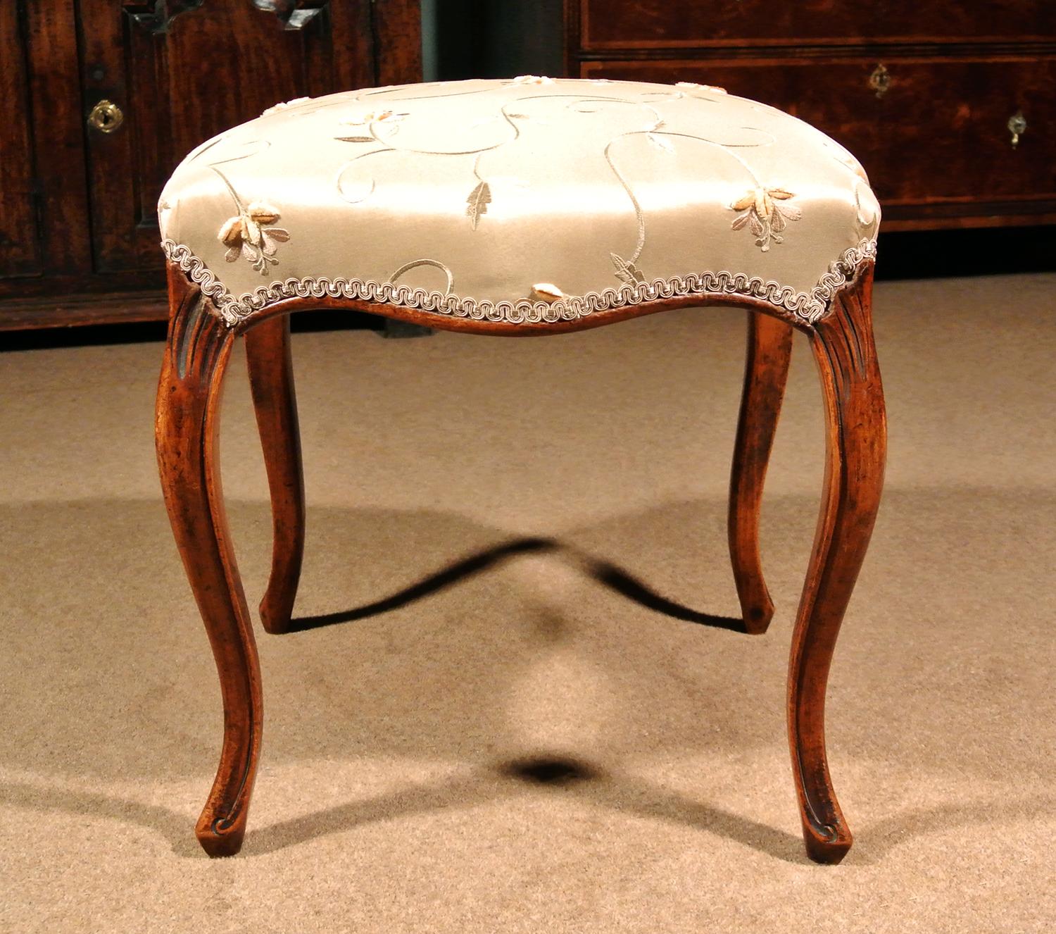 Of excellent colour and condition, a very elegant 19th century solid walnut stool.

Beautiful solid serpentine walnut seat rails and long cabriole legs with rolled channel carved borders and scrolled peg toes in the French manner.

The legs carved