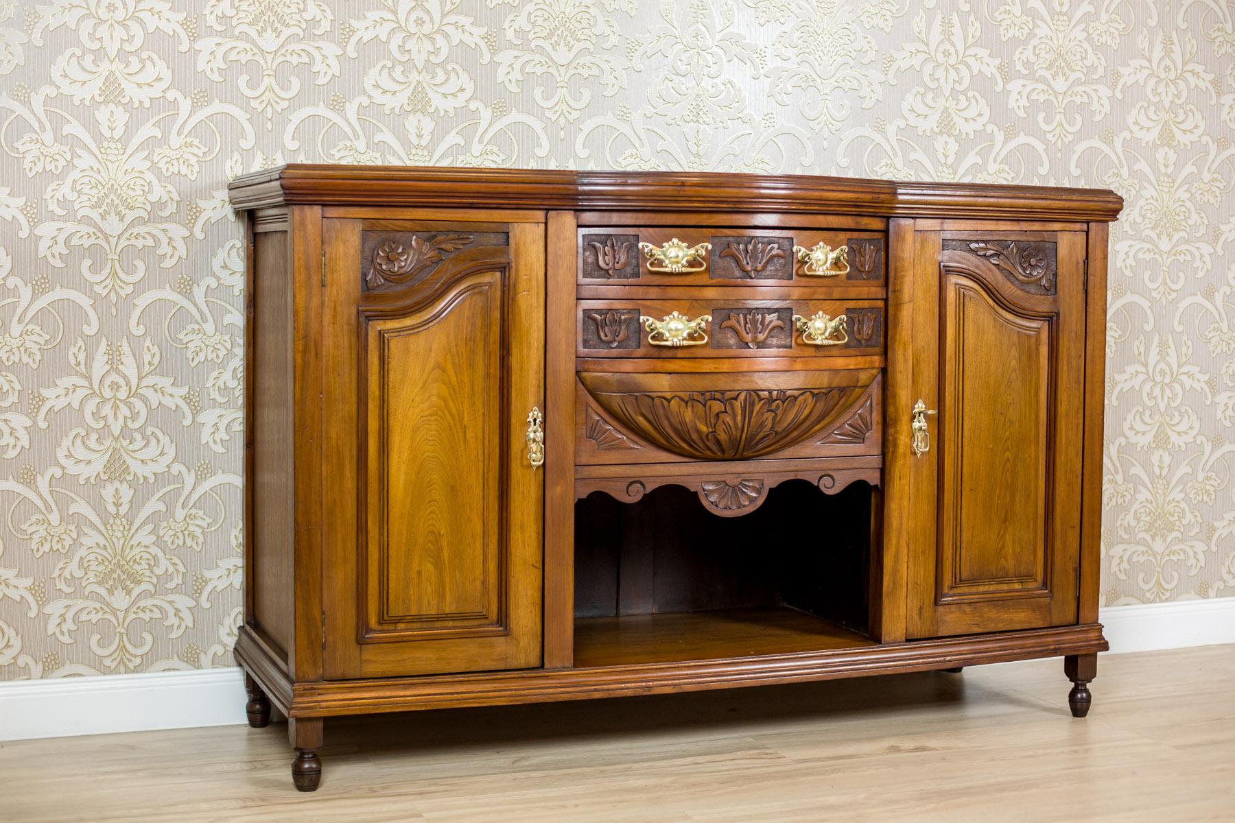 We present you this piece of furniture made of solid walnut wood.
The corpus has two cabinets on the outer sides. There are drawers in its central section, and a niche at the bottom.
Furthermore, there is a sort of an apron under the drawers with