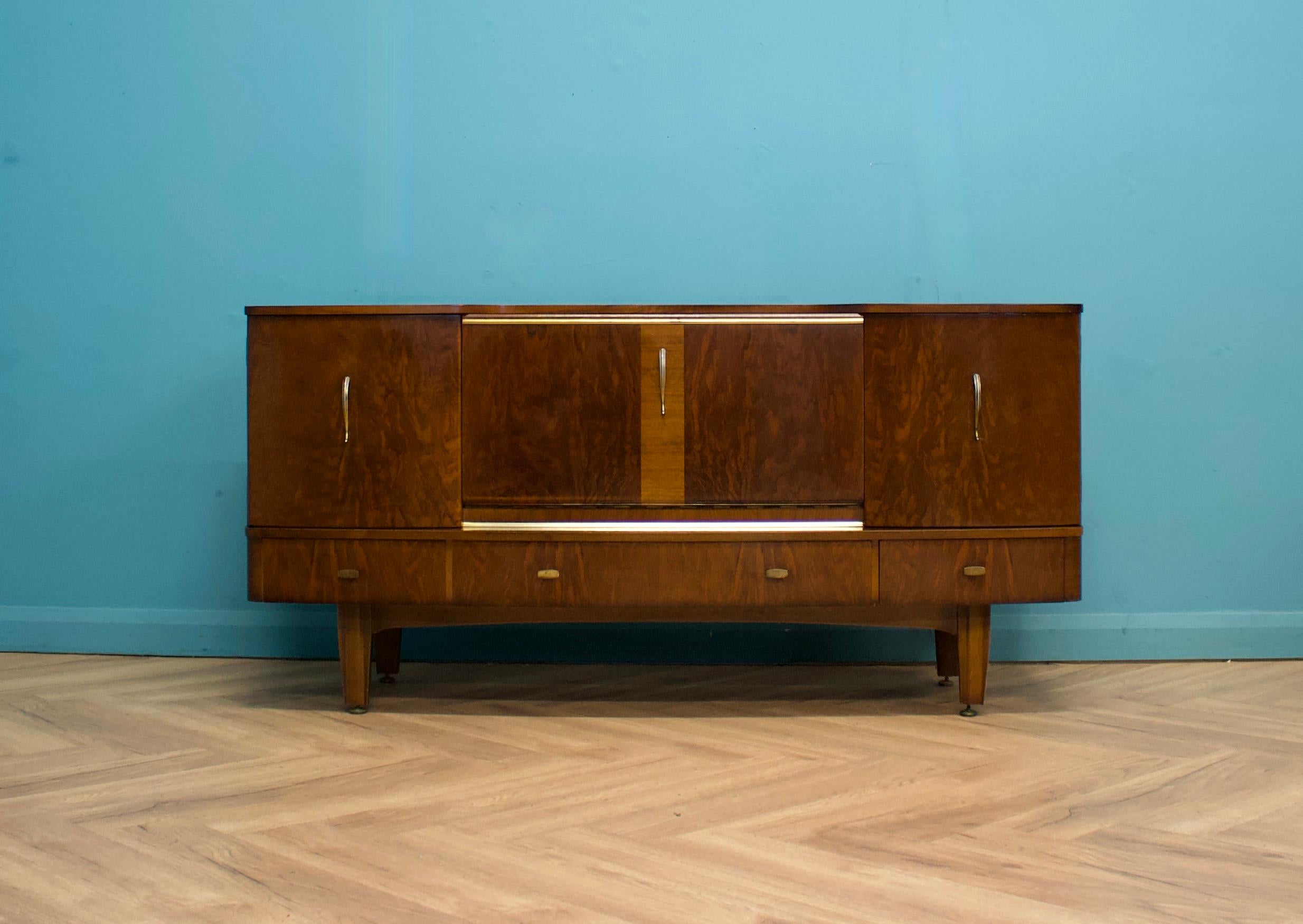 A mid century high gloss finish walnut sideboard or drinks cabinet from Stonehill, circa 1960s 

 

Featuring two cupboards - one with a shelf, three drawers and pull down drinks cabinet with a shelf