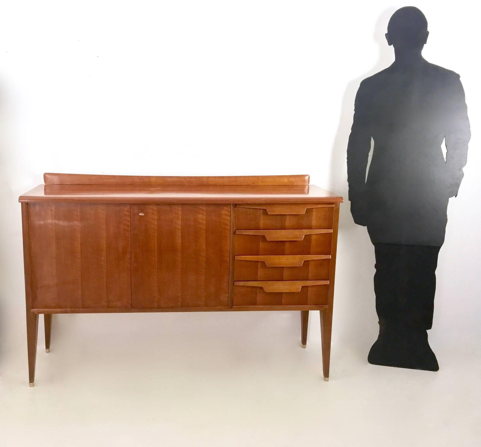 This sideboard is made in walnut and features maple interiors and solid brass feet caps.
Its drawers and legs recall Gio Ponti's design. 
It may show slight traces of use due to its age, but it has been polished perfectly with shellac and it is