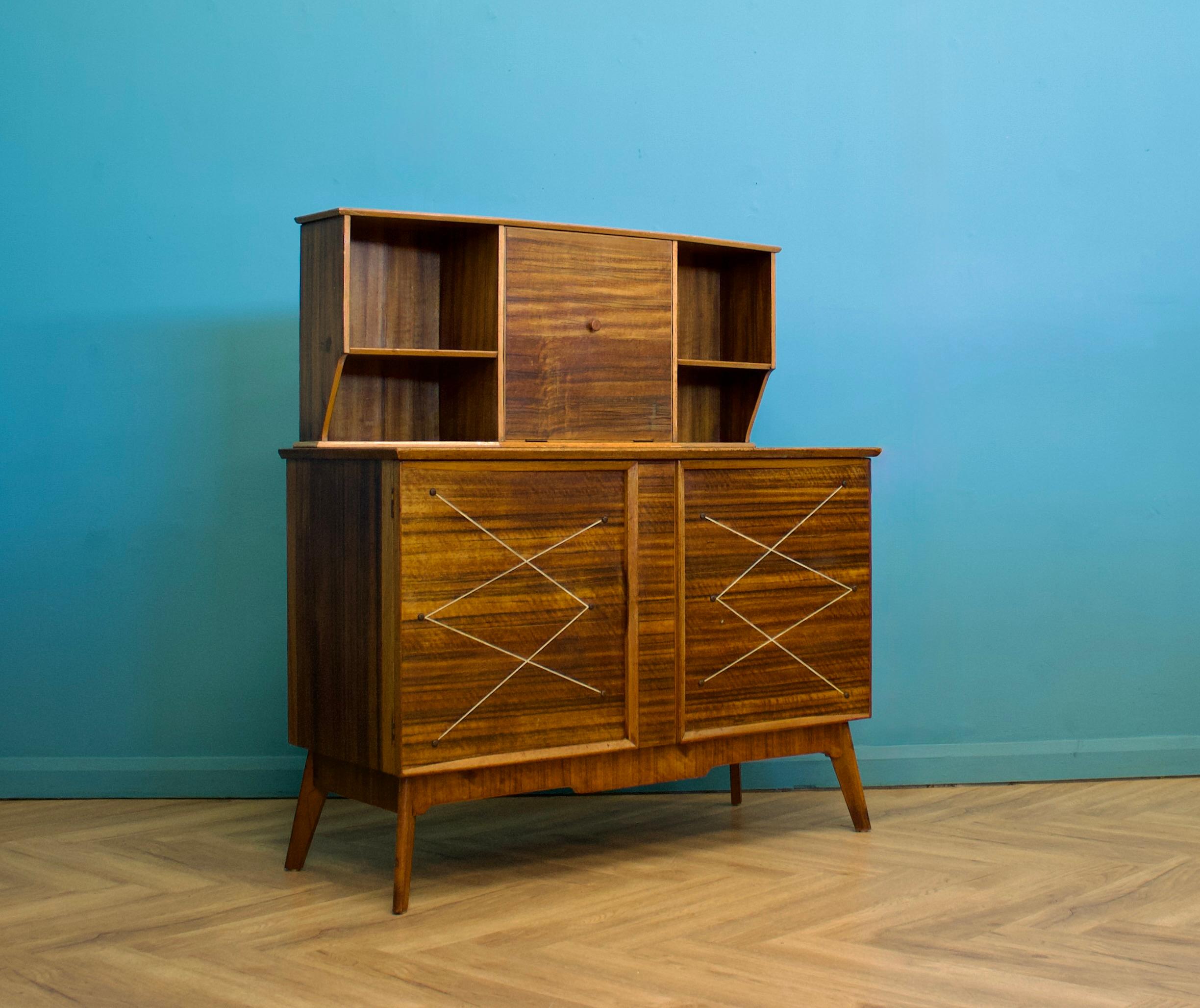 A mid century walnut sideboard or drinks cabinet from Alfred Cox, circa 1950s



Featuring two cupboards - with shelves, a drawer and pull down drinks cabinet with shelves to the top



The top section is removable of preferred