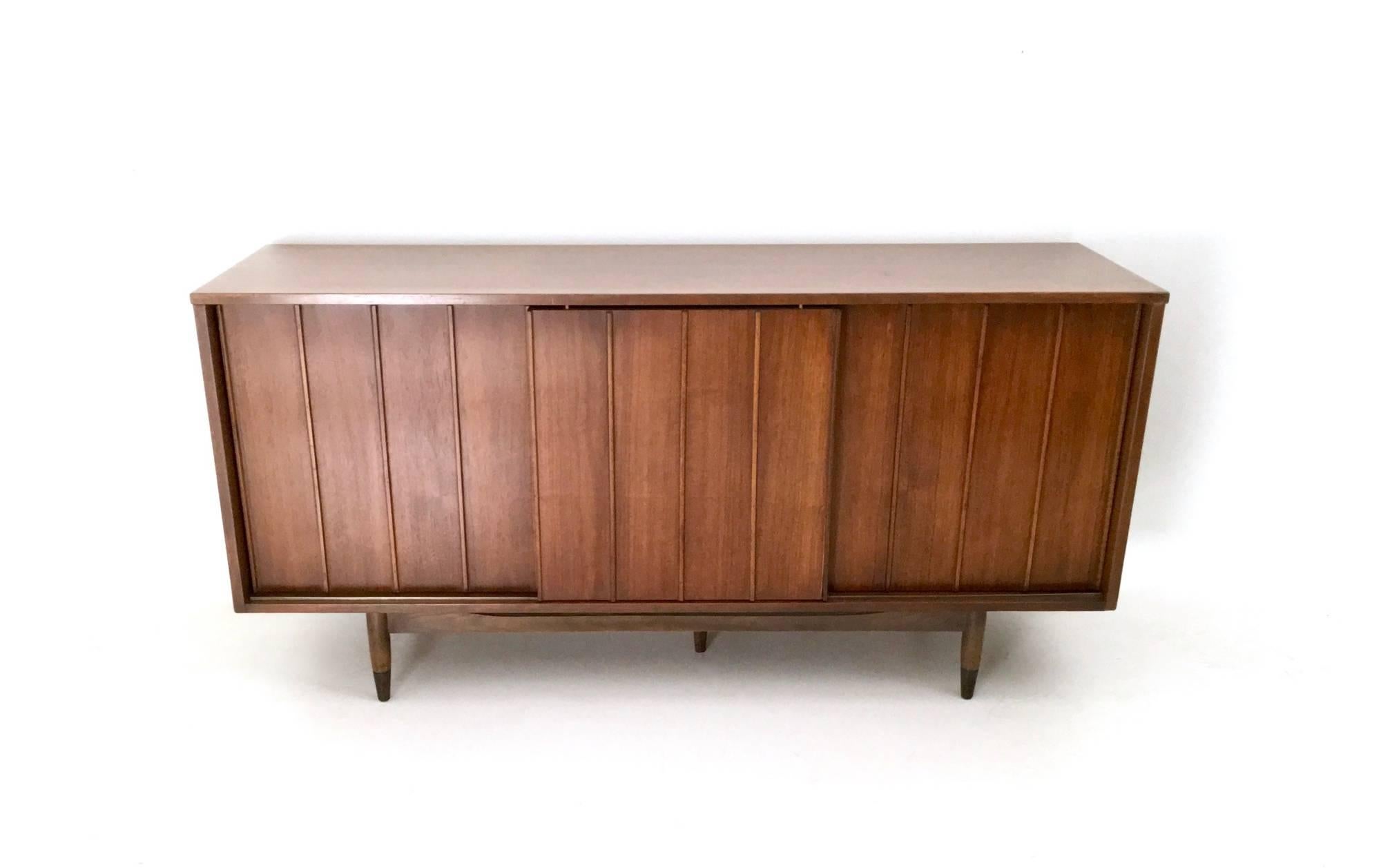 Made in walnut and braided bamboo.
Its doors are double-sided, combinable as you like.
This sideboard has an extractable shelf, that was probably designed as a TV stand, a glass shelf and three drawers.
In excellent original condition and ready
