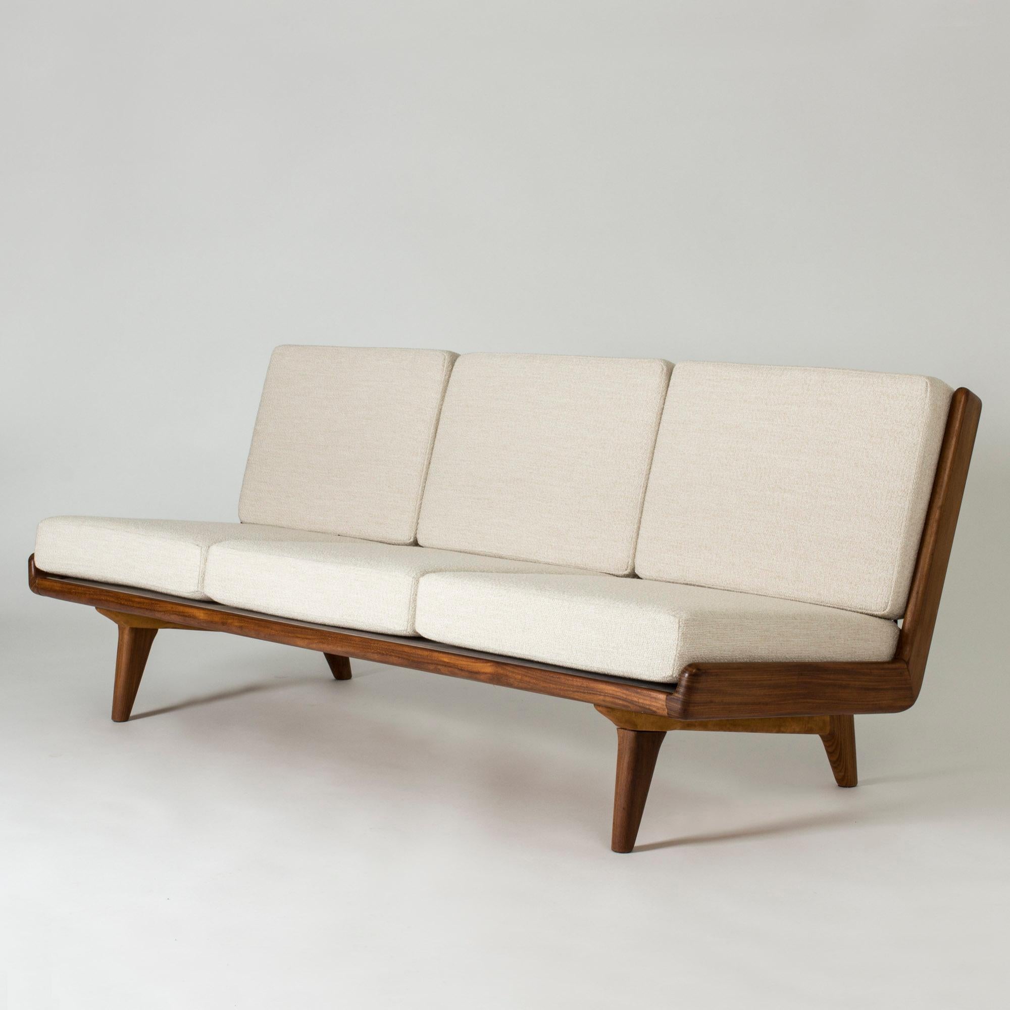 Sofa by Gustaf Hiort af Ornäs, made from walnut with sculptural details. The amazing leather webbing backrest makes this sofa a real room jewel. Seat upholstered in cream fabric.