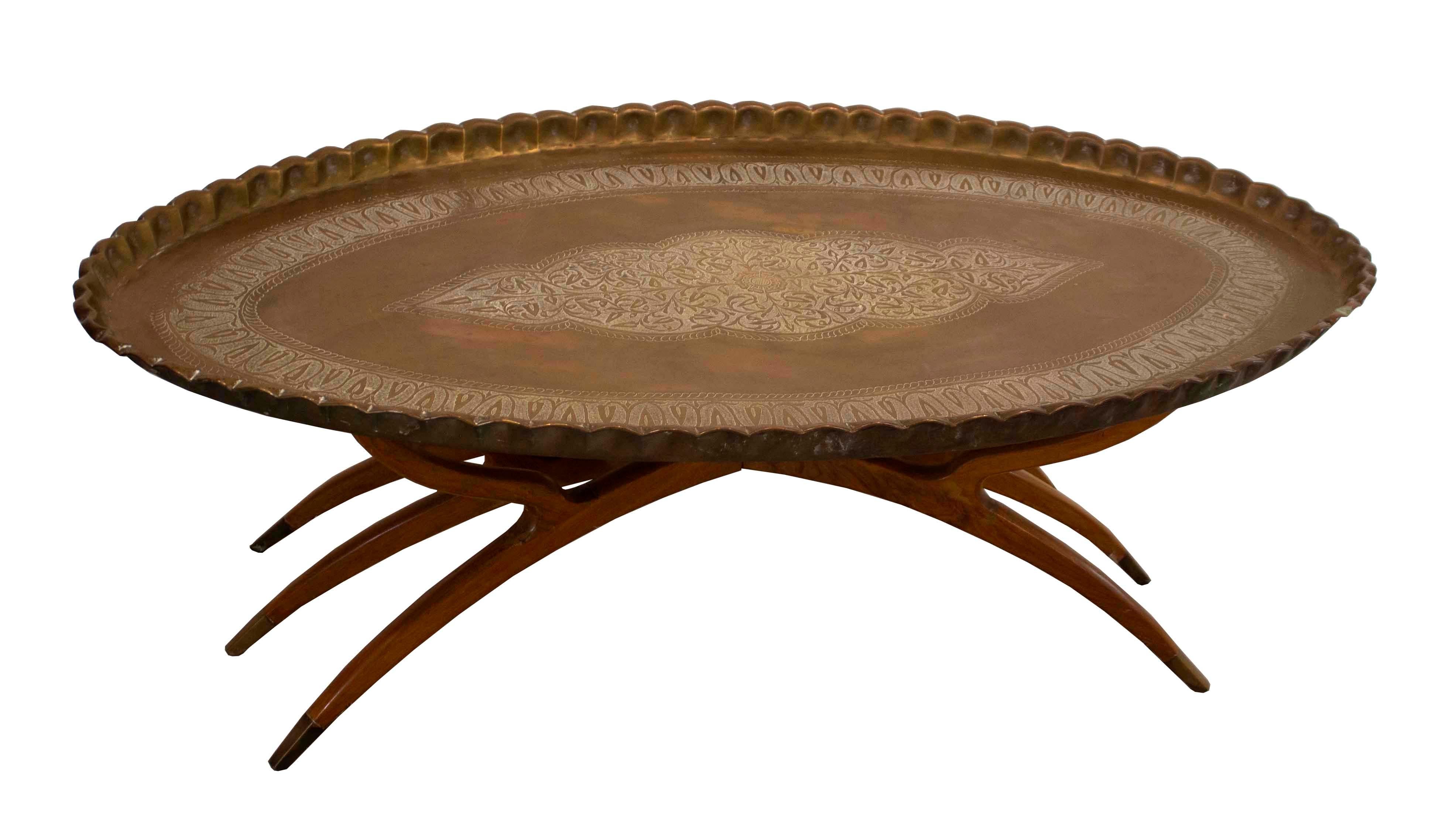 Up for consideration is Bohemian coffee table with collapsible walnut spider leg base and paired with its original Moroccan, hand-hammered 'pie' edge tray top, intricately carved. This look dovetails nicely with a wide range of styles from