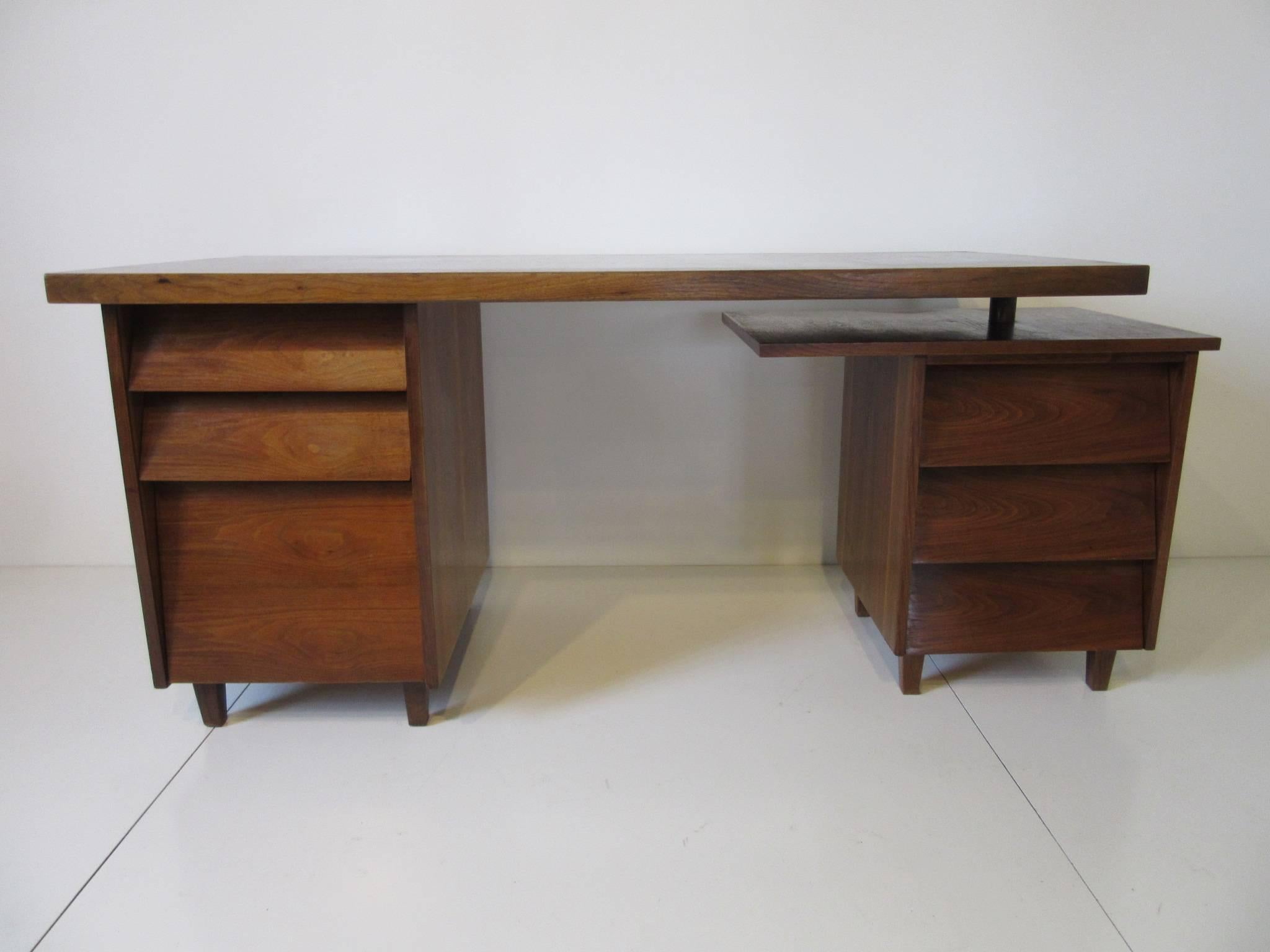 A dark well grained walnut desk which can swivel to any position and a swiveling small lower end platform for more work space. Five drawers and a file totaling six with plenty of storage, this desk can be used in many different ways in a room