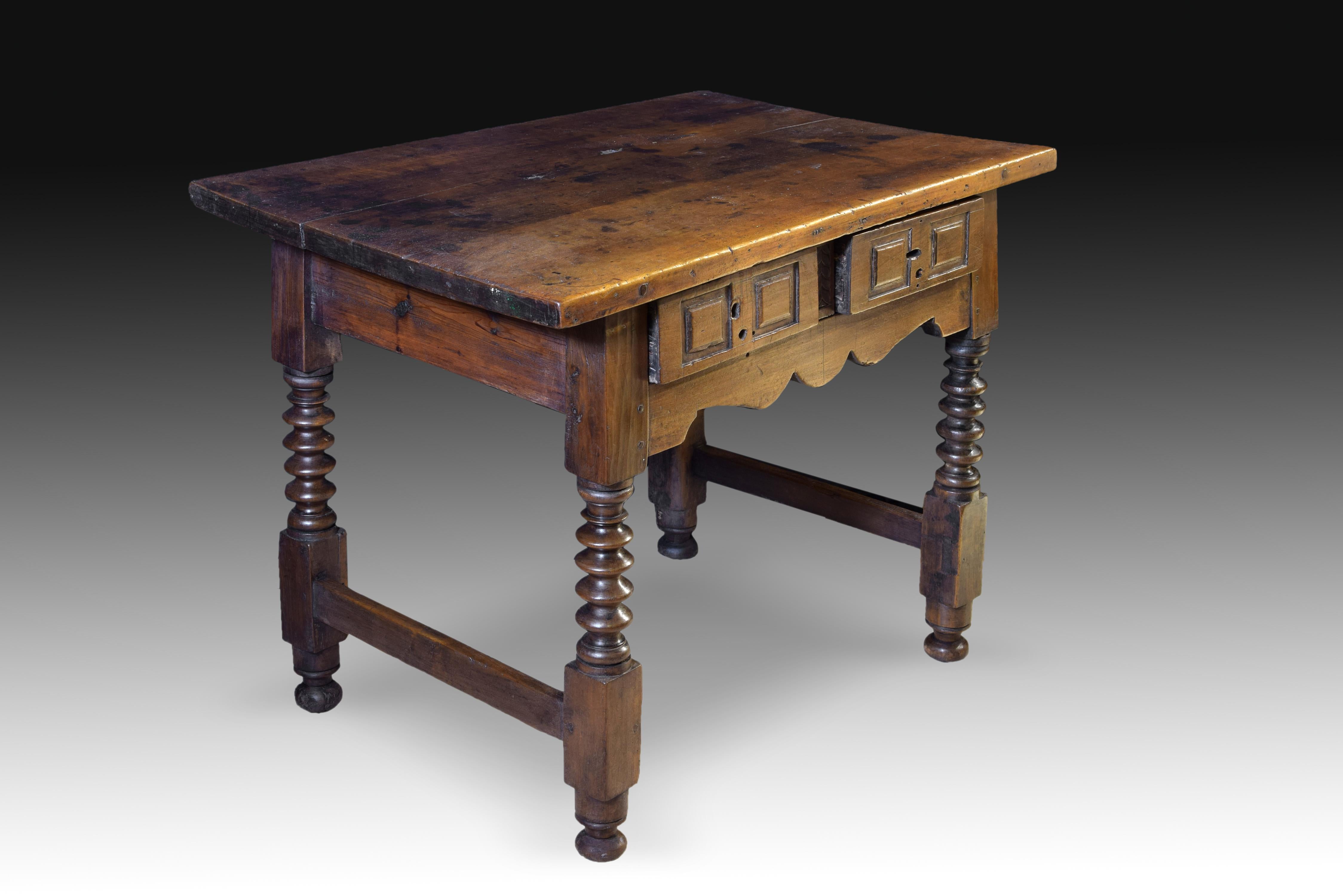 Walnut table. 17th century.
Table with smooth rectangular board and two drawers to the front, decorated with simple geometric shapes on their fronts, leaving between them a strip with tabs. The legs, united in their lower rectangular knot by a