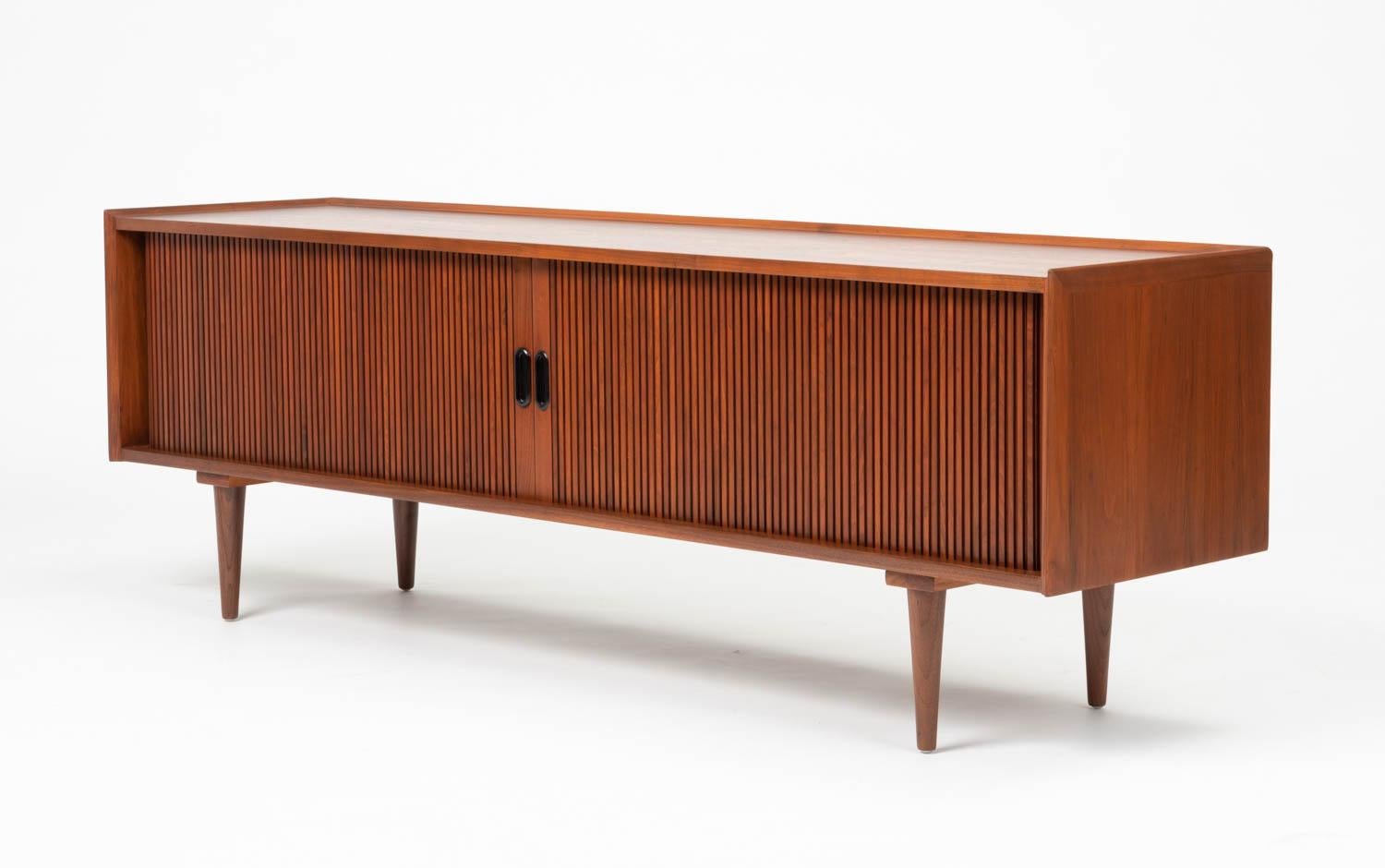 American made walnut credenza designed by Merton L. Gershun for Dillingham features two tambour doors that open to expose three multicolored drawers flanked by divided cabinets for record storage. 

Condition: Professionally refinished.