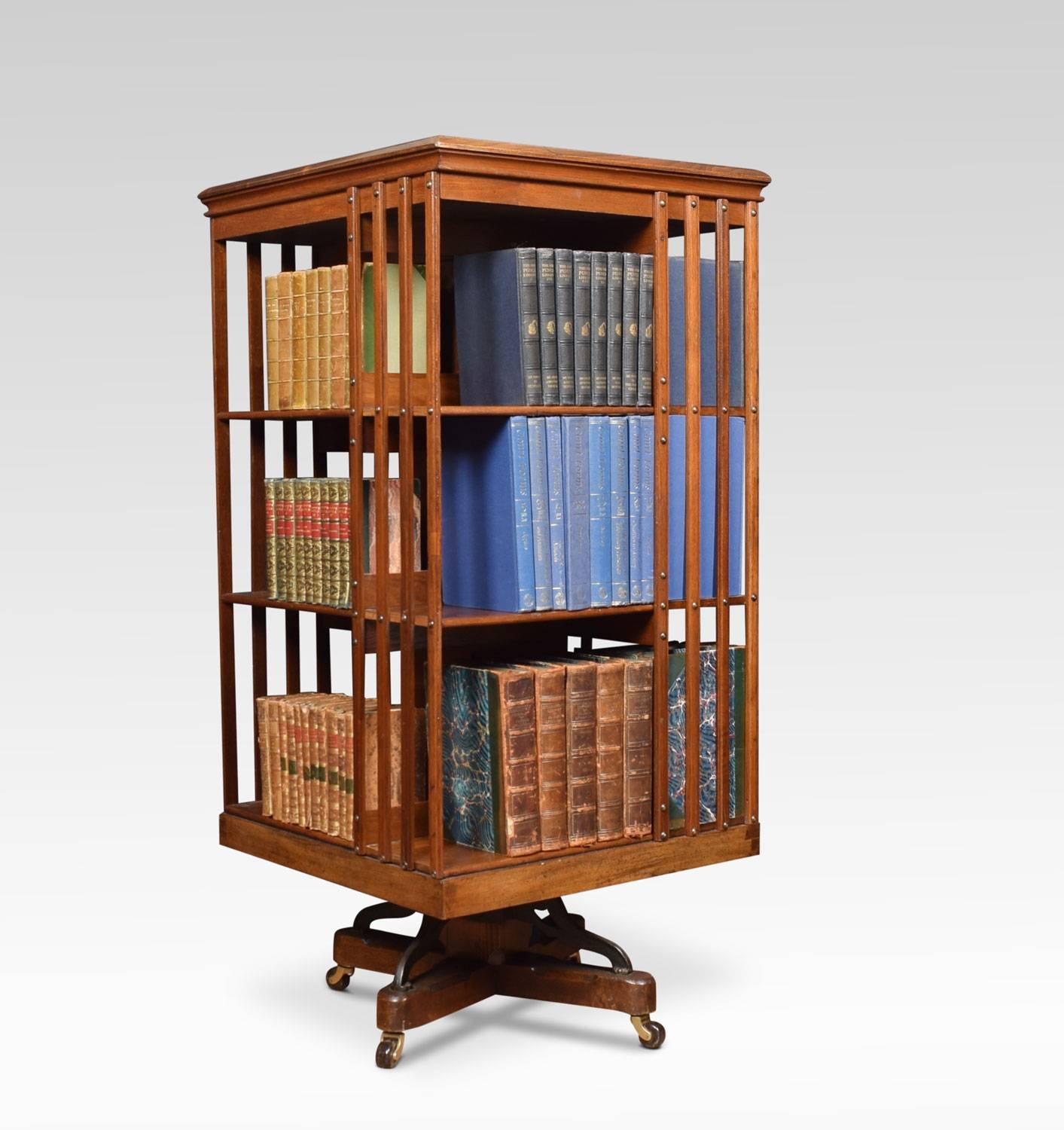 Large Edwardian walnut three-tier revolving bookcase, the square moulded top above an arrangement off shelves raised up on cruciform base with metal support. Terminating in brass caps and ceramic castors. The bookcase displaying stamp, the American