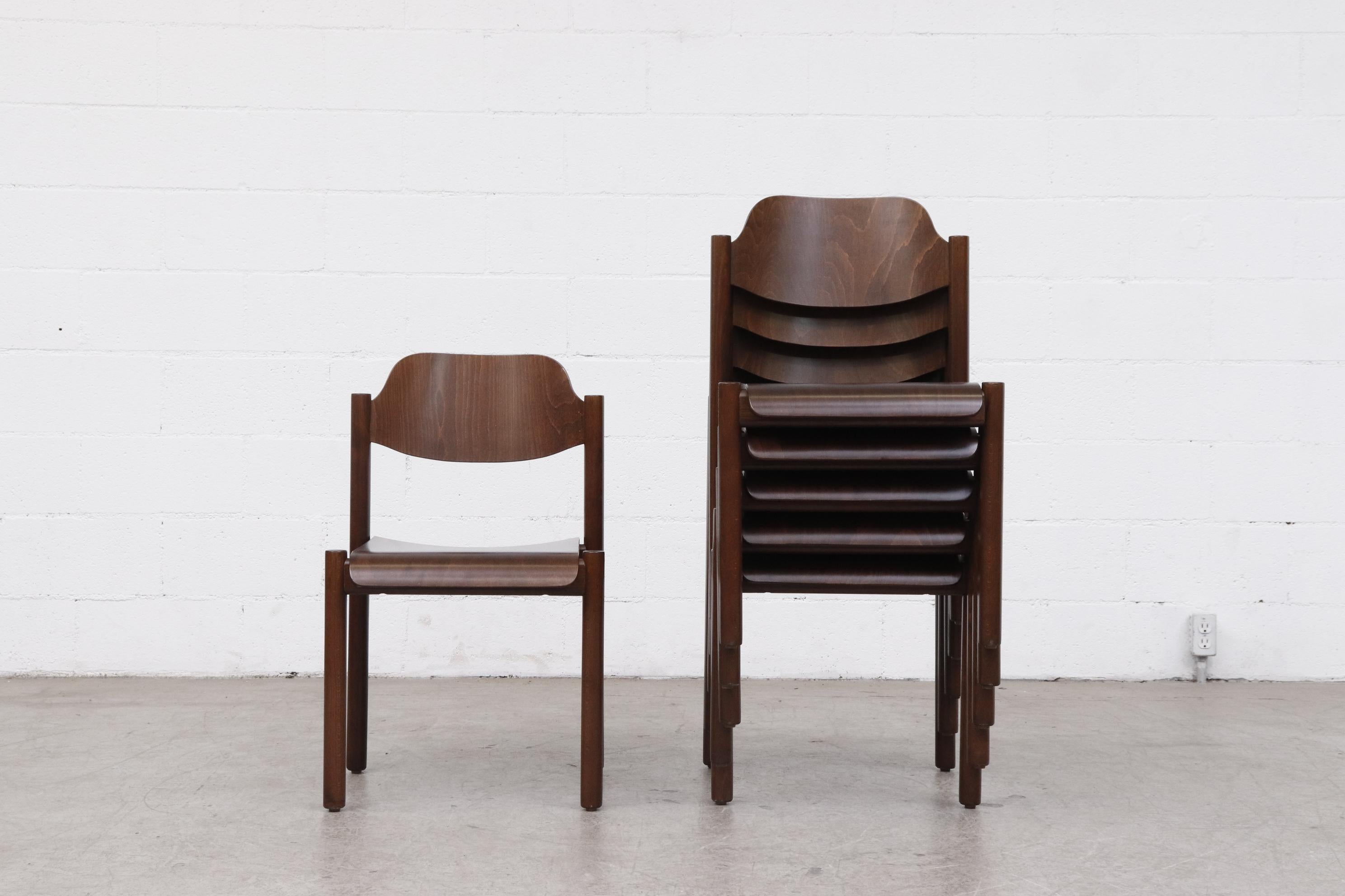 Dark Walnut Toned Stacking Wood Chairs. Formed Plywood Seats and Backs with Round Legs   Inset Seats for Convenient Stacking. In Original Condition with Visible Patina and Wear Consistent with their Age and Use. Priced Individually.
Lead time from
