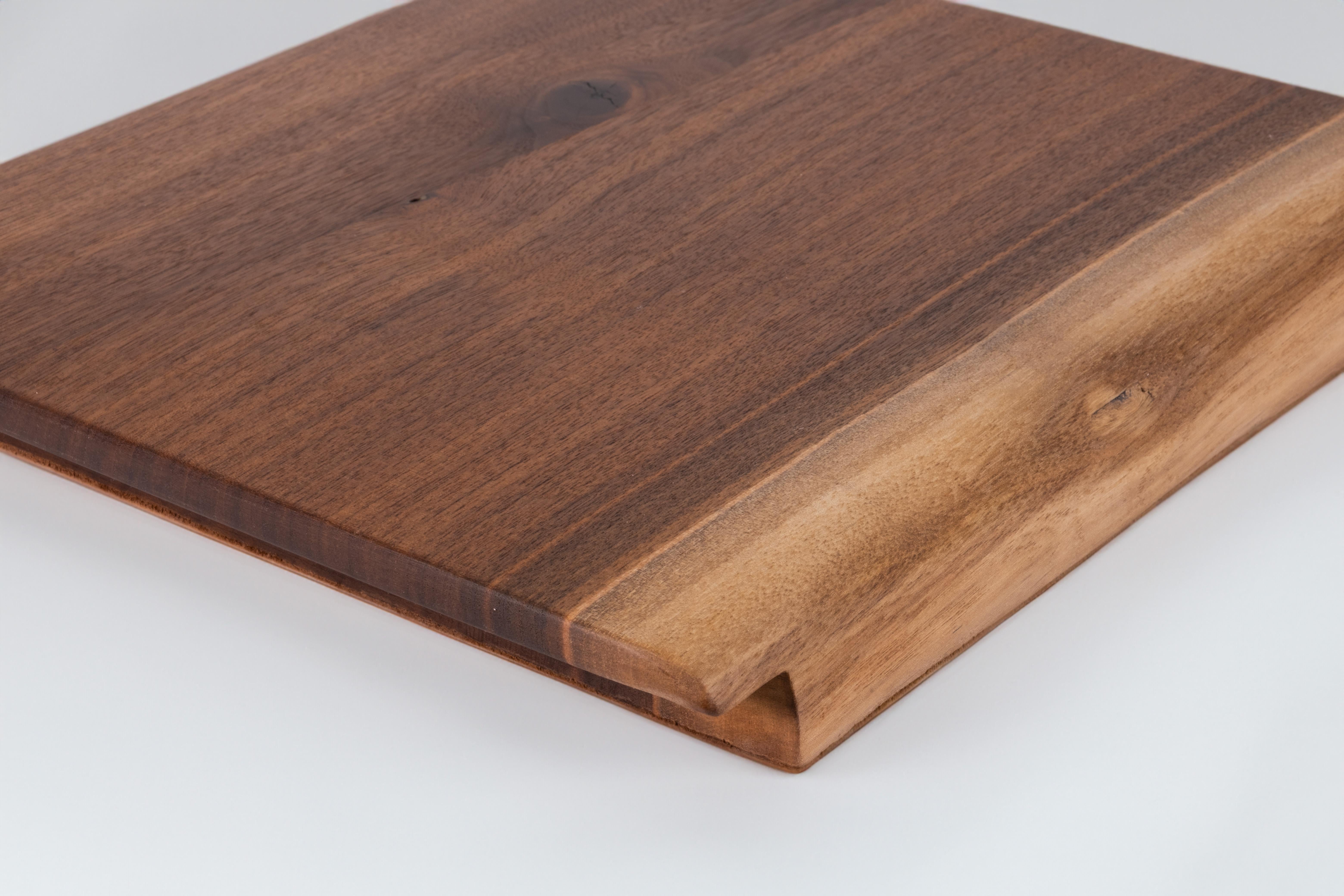 This stunning piece features a unique design where one edge showcases the captivating live edge of the walnut wood, celebrating its natural beauty. The bottom of the tray is elegantly covered in leather, adding a touch of luxury and ensuring a soft
