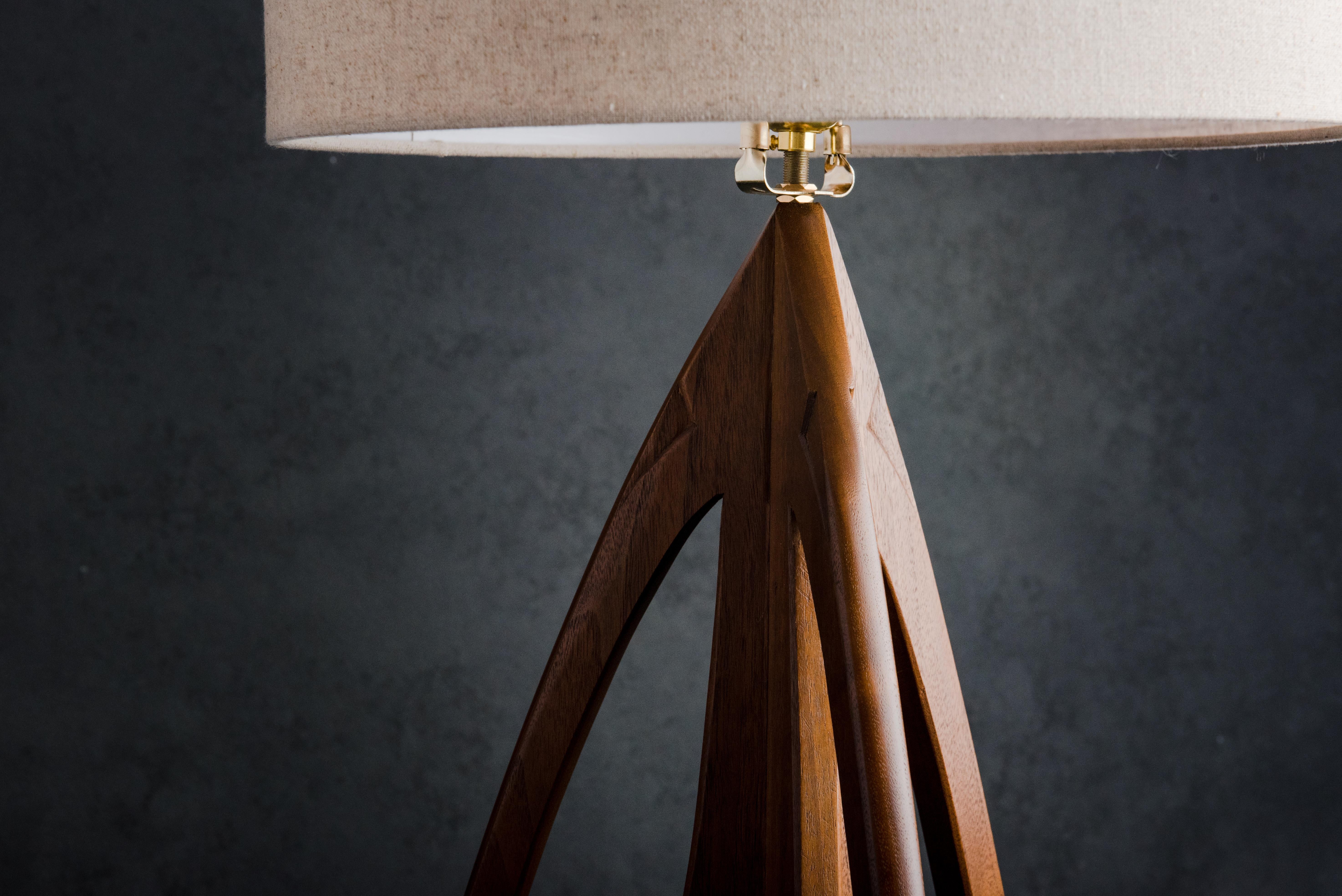 The base is formed by three parts lifting from the floor and coming together, accented by hand shaping to create a sculpture that happens to light up a room. The cord is discreetly hidden down the edge of a leg. 

The lamp (not including the shade)