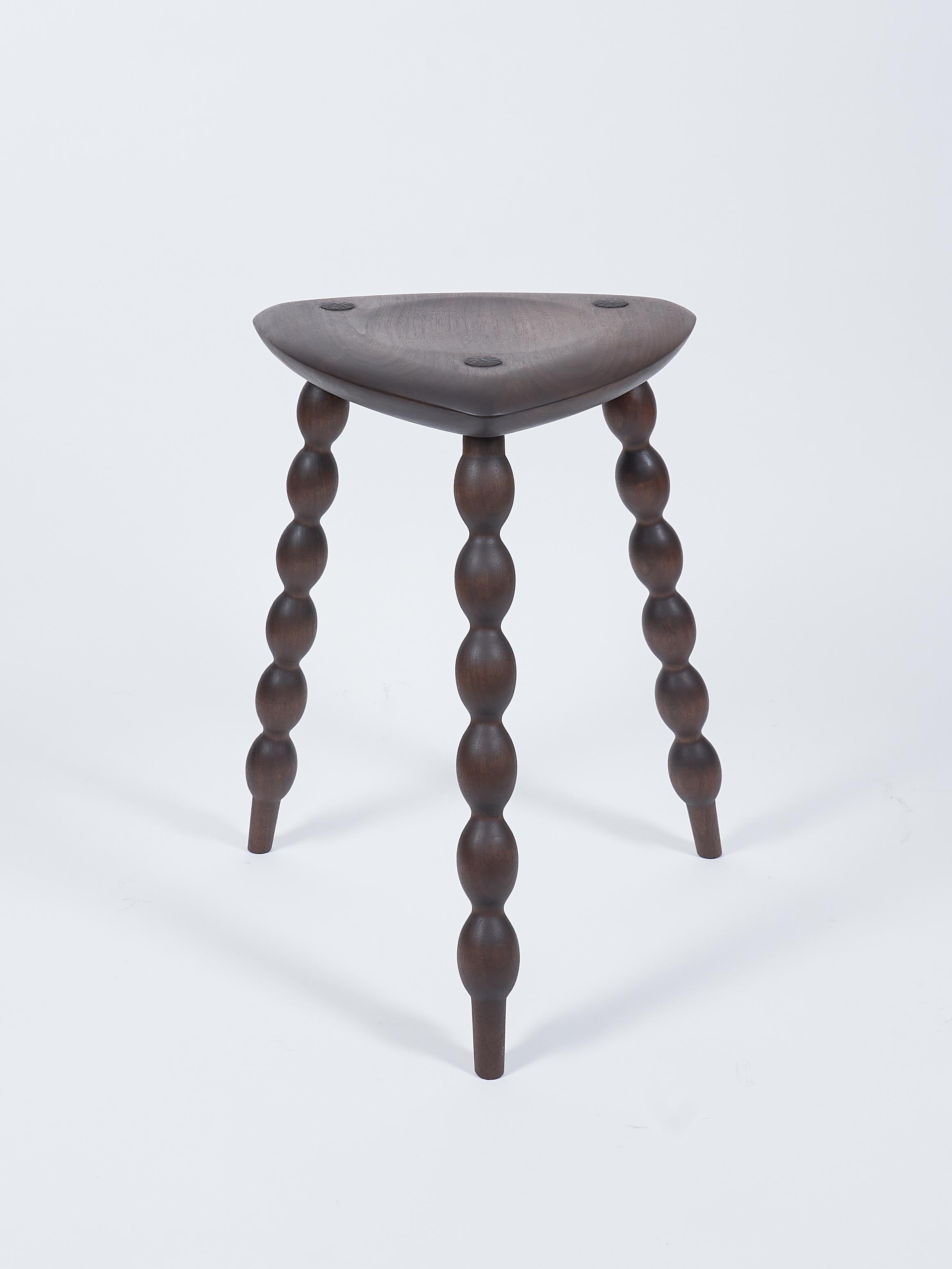 Walnut Tripod Stool with Turned Bobbin Legs and Carved Seat designed and built by Val Khvan.

This handcrafted walnut tripod stool brings together bold detailing and subtle refinement. The solid walnut seat is thoughtfully carved for comfort,