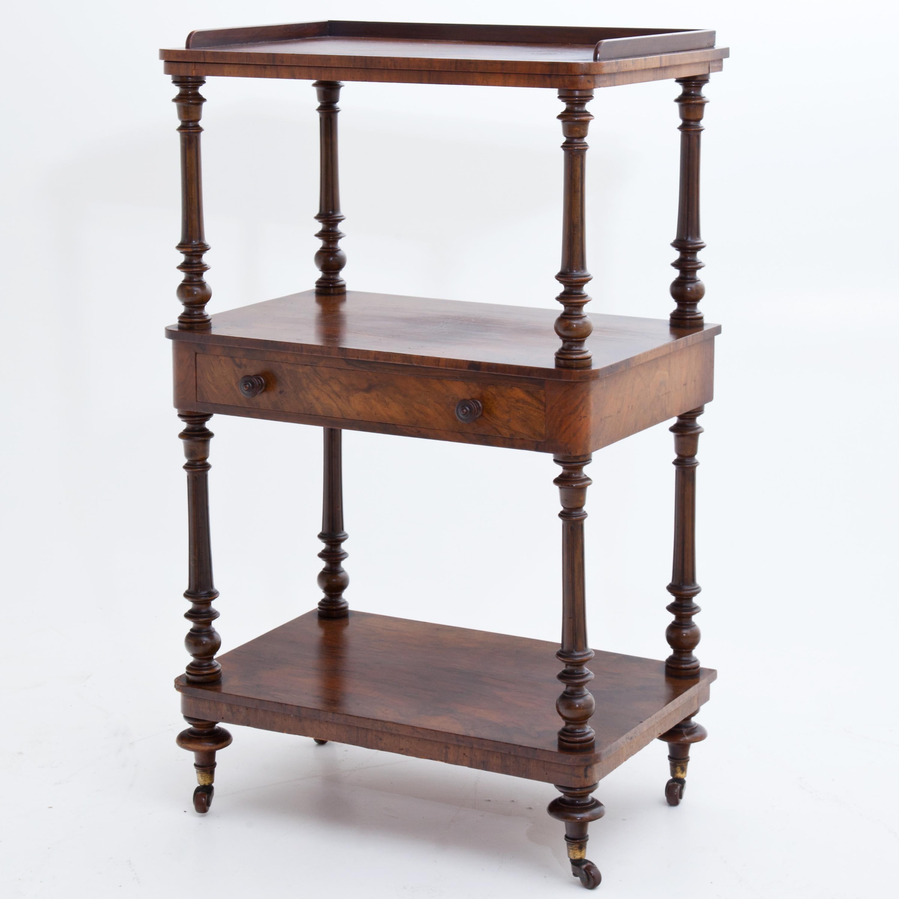 English two-tier walnut shelf on castors with one drawer and turned balustered columns.