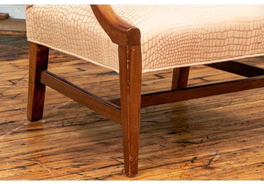 Modern lines to the frame with curved arms and square tapering legs with H stretcher. Upholstered in a pink and cream croco print fabric. 

Dimensions: H. 42