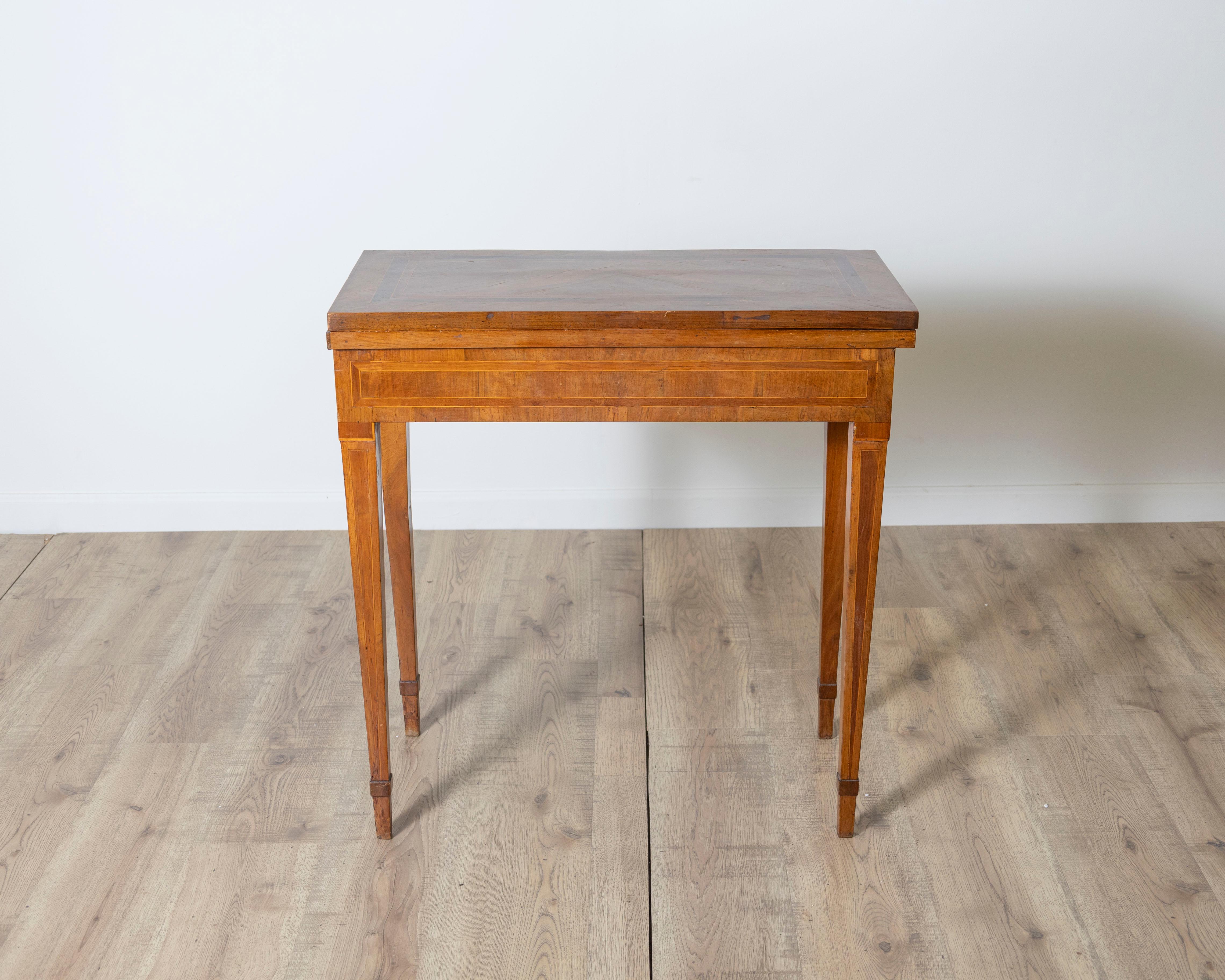 Une élégante table de jeu italienne de la fin du XVIIIe siècle, réalisée en placage de noyer avec des incrustations raffinées. Le plateau rectangulaire est encadré d'incrustations linéaires et s'ouvre pour révéler en son centre une surface en damier