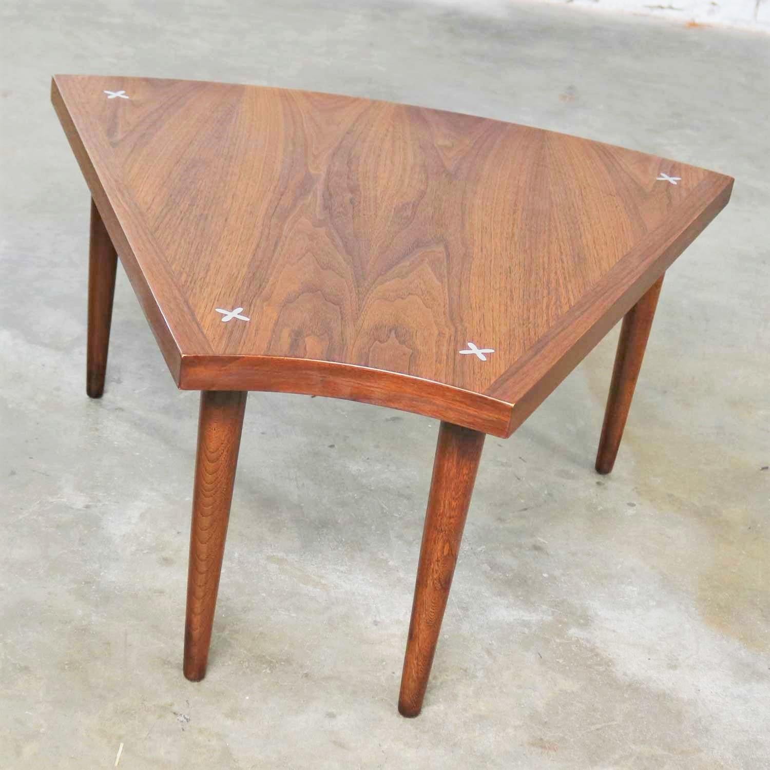 Handsome wedge or pie shape end, side, or occasional table in walnut with inlaid aluminum X’s attributed to Merton Gershun for American of Martinsville. It is in wonderful vintage condition. The top has been restored and is beautiful, but it still