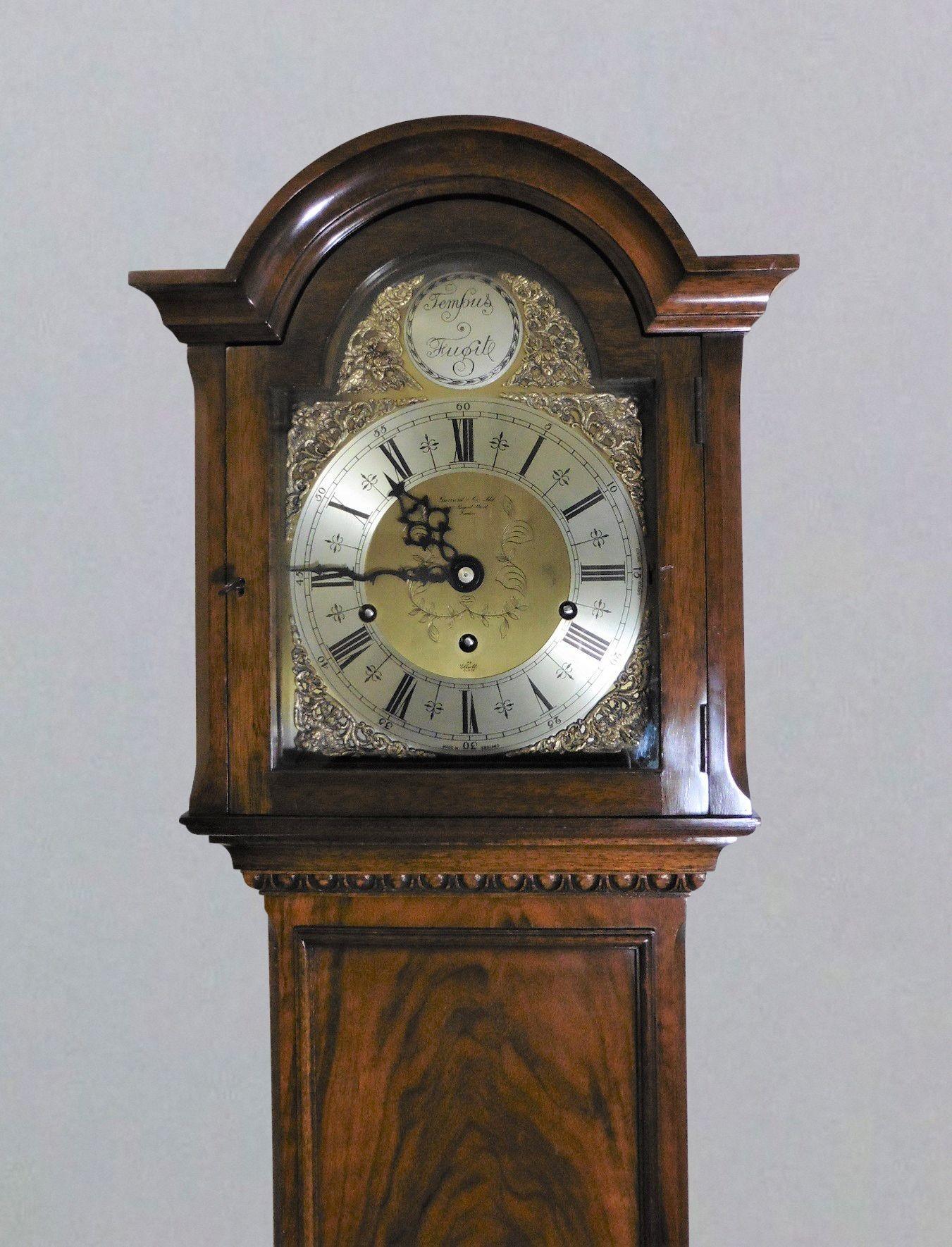 Walnut grandmother clock retailed by Garrards.

Walnut Longcase clock standing on a raised, shaped moulded plinth with applied panel to the base and carved acanthus leaf decoration.

Faux long trunk door with raised edging below the break arch