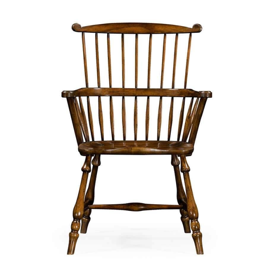 Traditional Windsor style walnut armchair with a distressed finish, the curved top rail, and arms above two registers of spindle supports. Solid shaped seat above a swollen central stretcher and splayed turned legs. 

Dimensions: 26