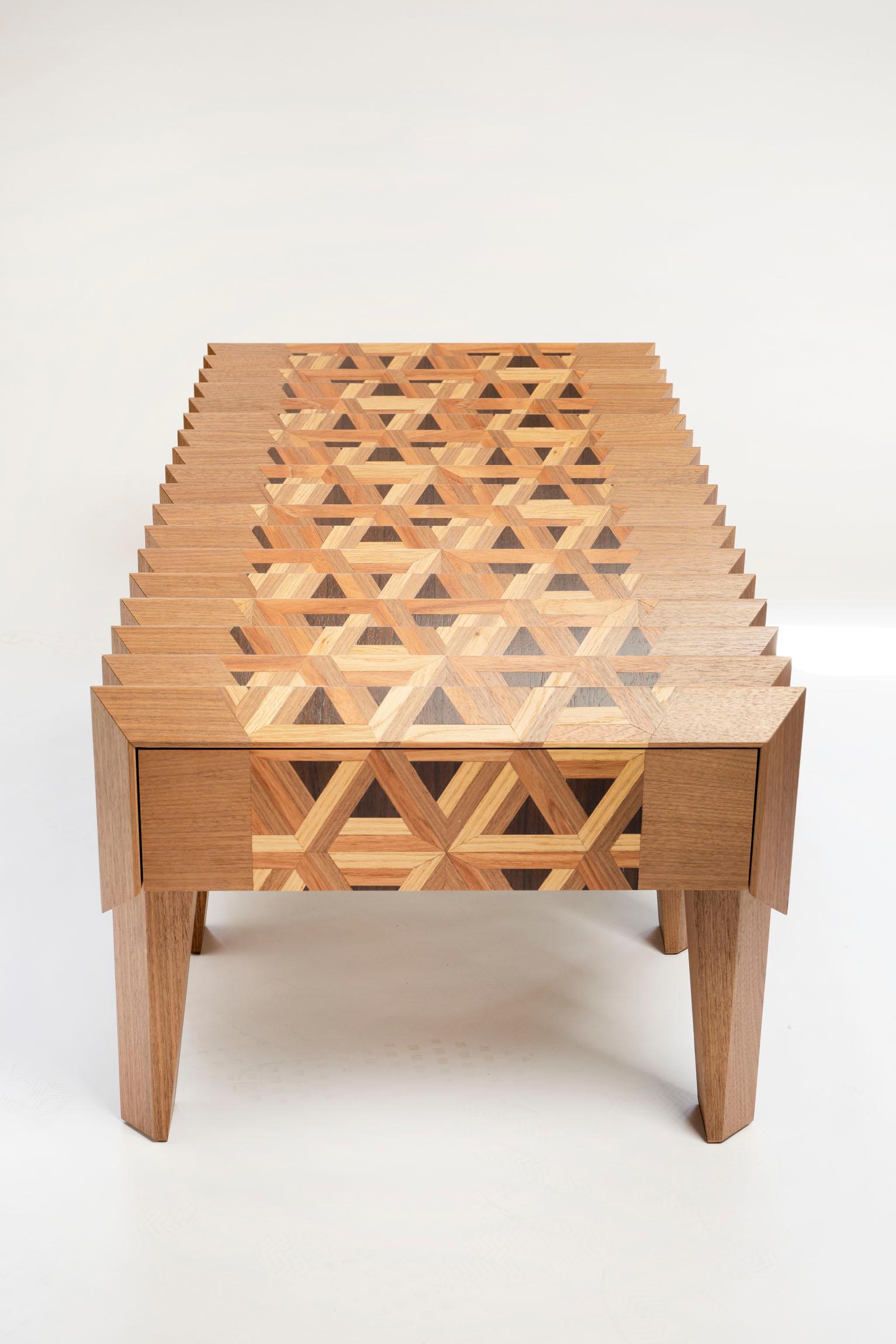 The Tavolo in Metamorfosi is a coffee table which consists of a top of triangles with a specially processed glass plate on top. If you look over the table on the short sides, you will see a 3D cube pattern and another pattern from the other side.
