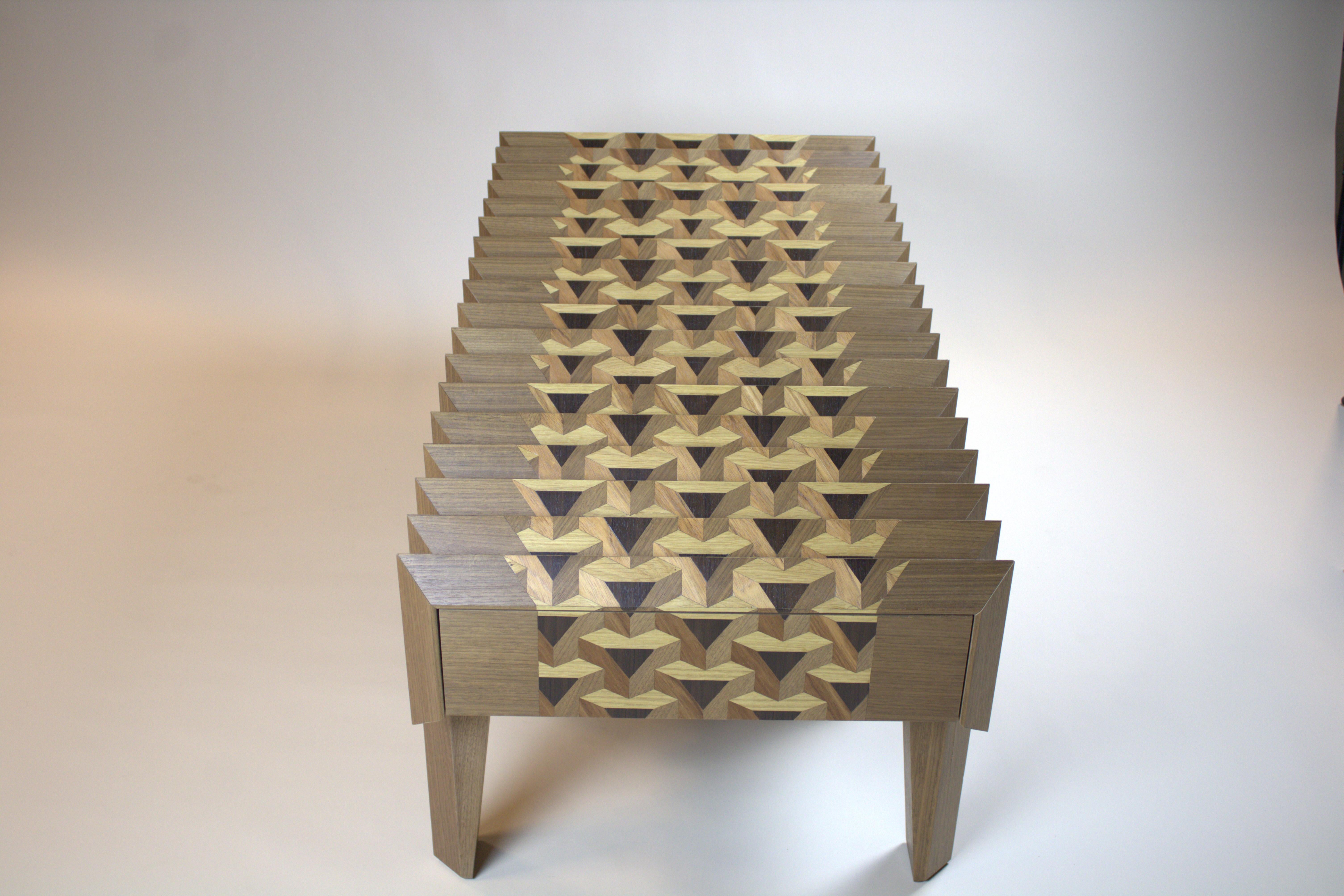 The Tavolo in Metamorfosi is a coffee table which consists of a top of triangles with a specially processed glass plate on top. If you look over the table on the short sides, you will see a 3D cube pattern and another pattern from the other side.