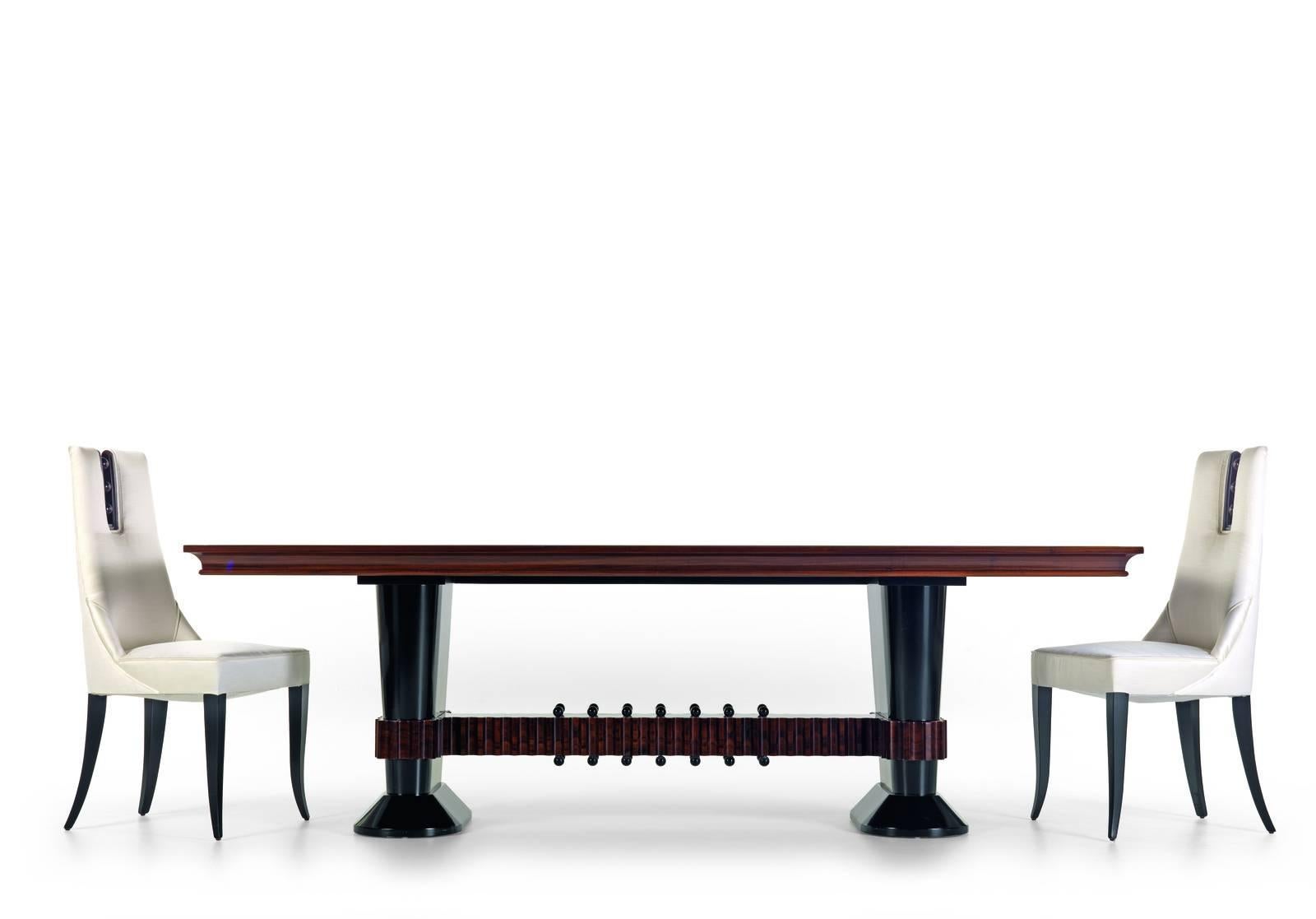 The structure of this elegant dining table was made in walnut wood and its two sets of legs are held together at the bottom by an element, also in walnut, that is accented by striking grooves and knots and functions as a footrest. Its finish is the