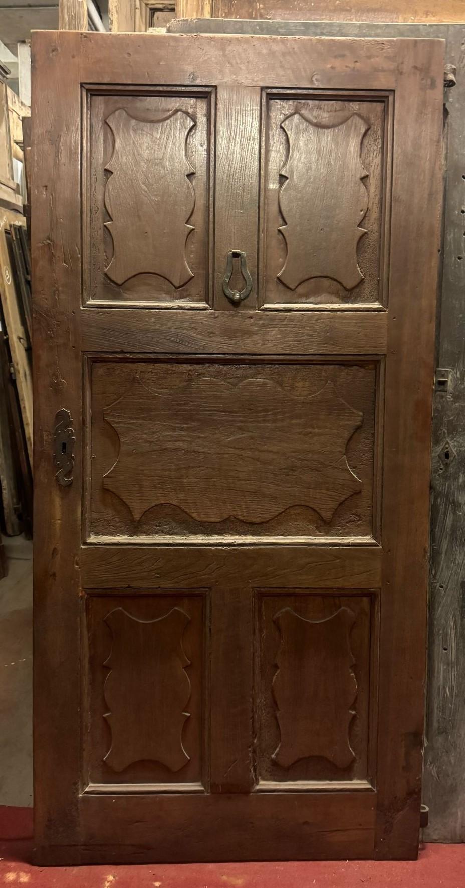 Porte d'entrée en bois de noyer, porte principale à un vantail avec 5 panneaux ondulés sculptés avec des carreaux typiques de l'époque, complète avec heurtoir, charnières (pousser à droite) et serrure d'origine (à réviser), d'origine du 18ème