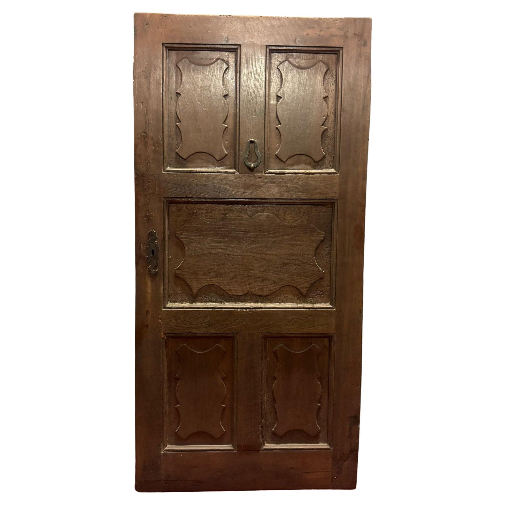 Walnut wood entrance door with one-leaf door and carved wavy panels, Italy
