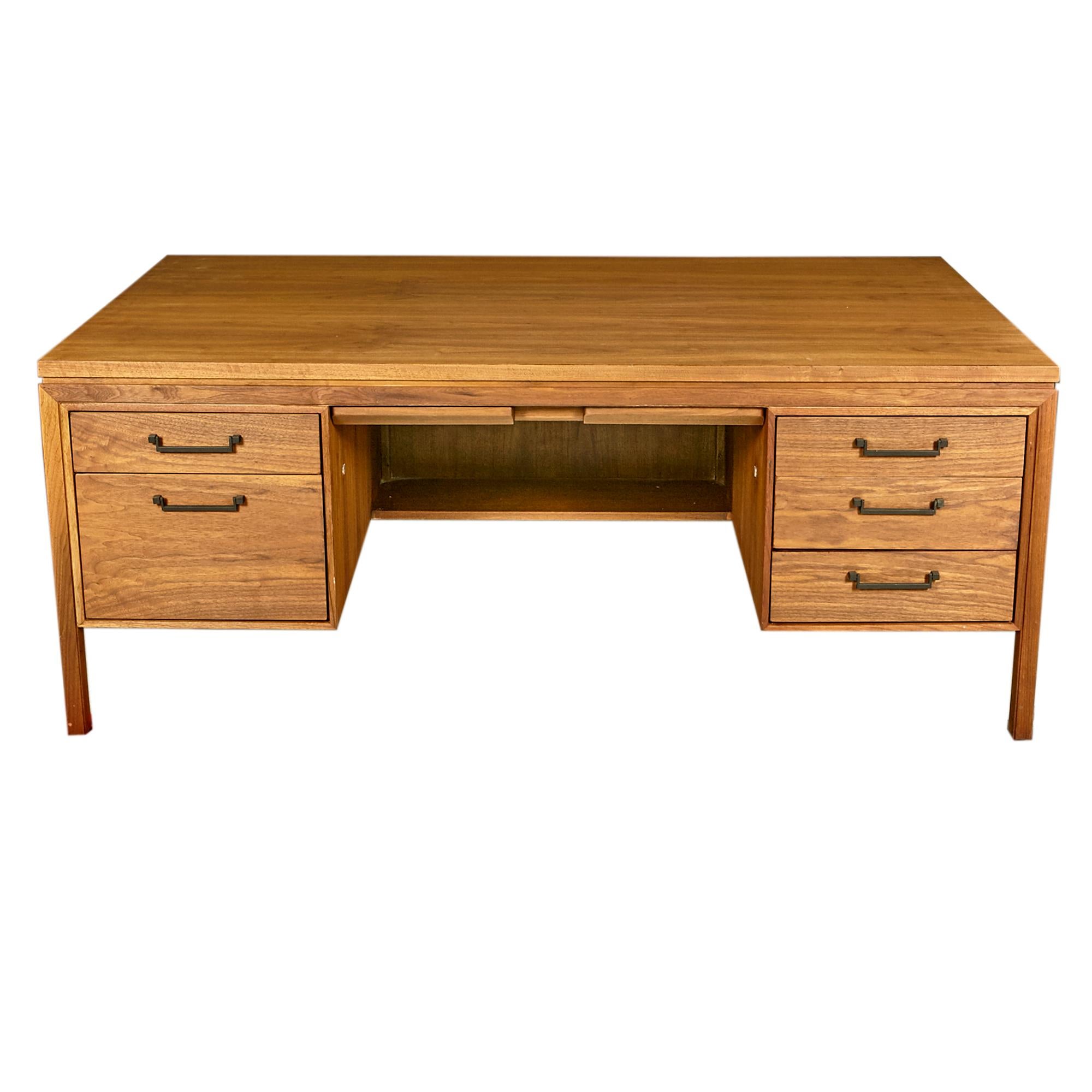 Vintage 1960s walnut wood double sided executive desk with black metal pulls. The desk has seven drawers for storage. In newly refinished condition. There are several scratches in the wood that remain. Marked.
 