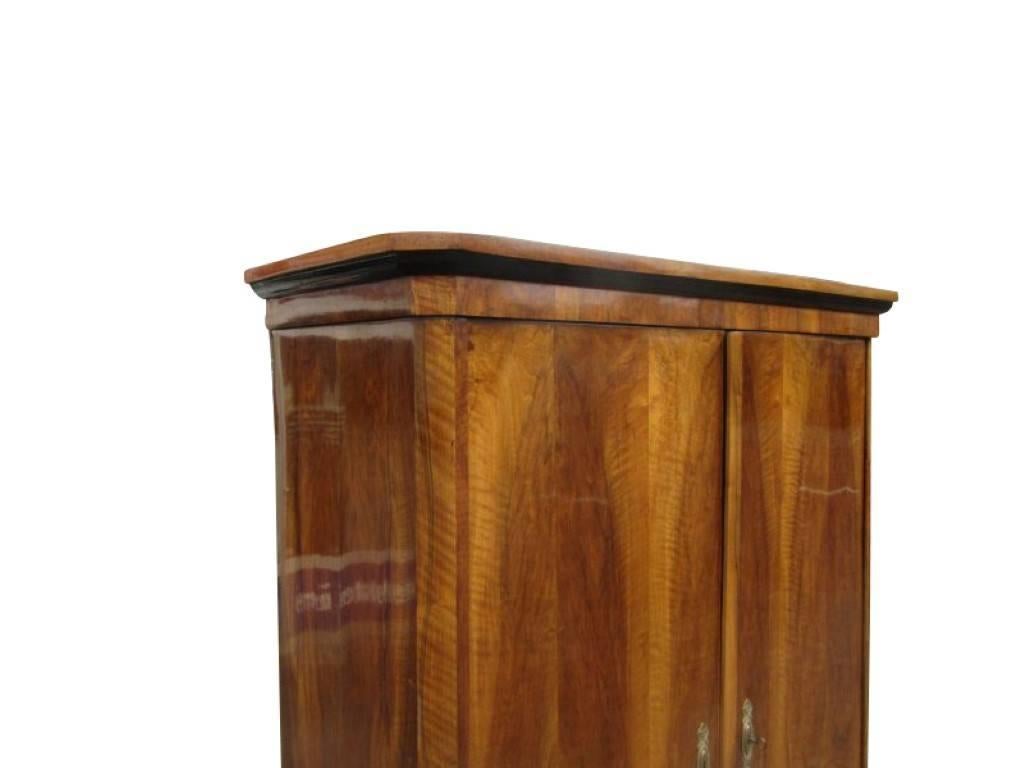 A Biedermeier wardrobe manufactured, circa 1840. The Body is made of solid softwood and is veneered with walnut wood. The surface of the piece has a wonderful wood pattern and a magnificent light-brown color tone. Inactive worm traces were filled