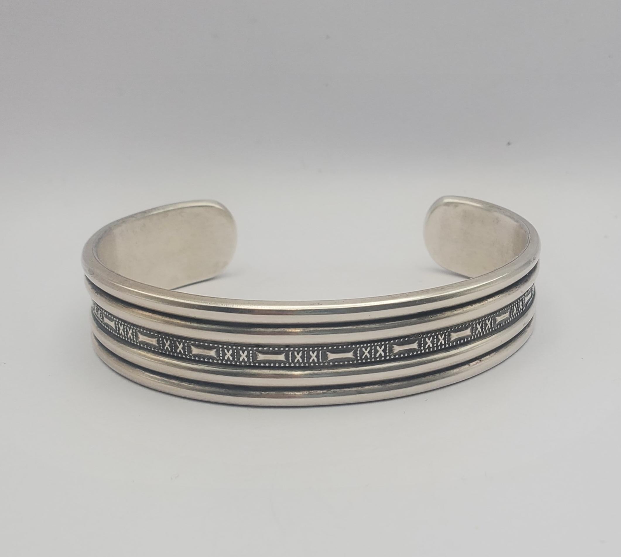 Substantial heavily stamped sterling silver cuff bracelet by master silversmith Walt Doran from the late 1990s. This cuff features hand-applied stamp work in the Navajo Native American style. There is a natural patina on the piece that we have not