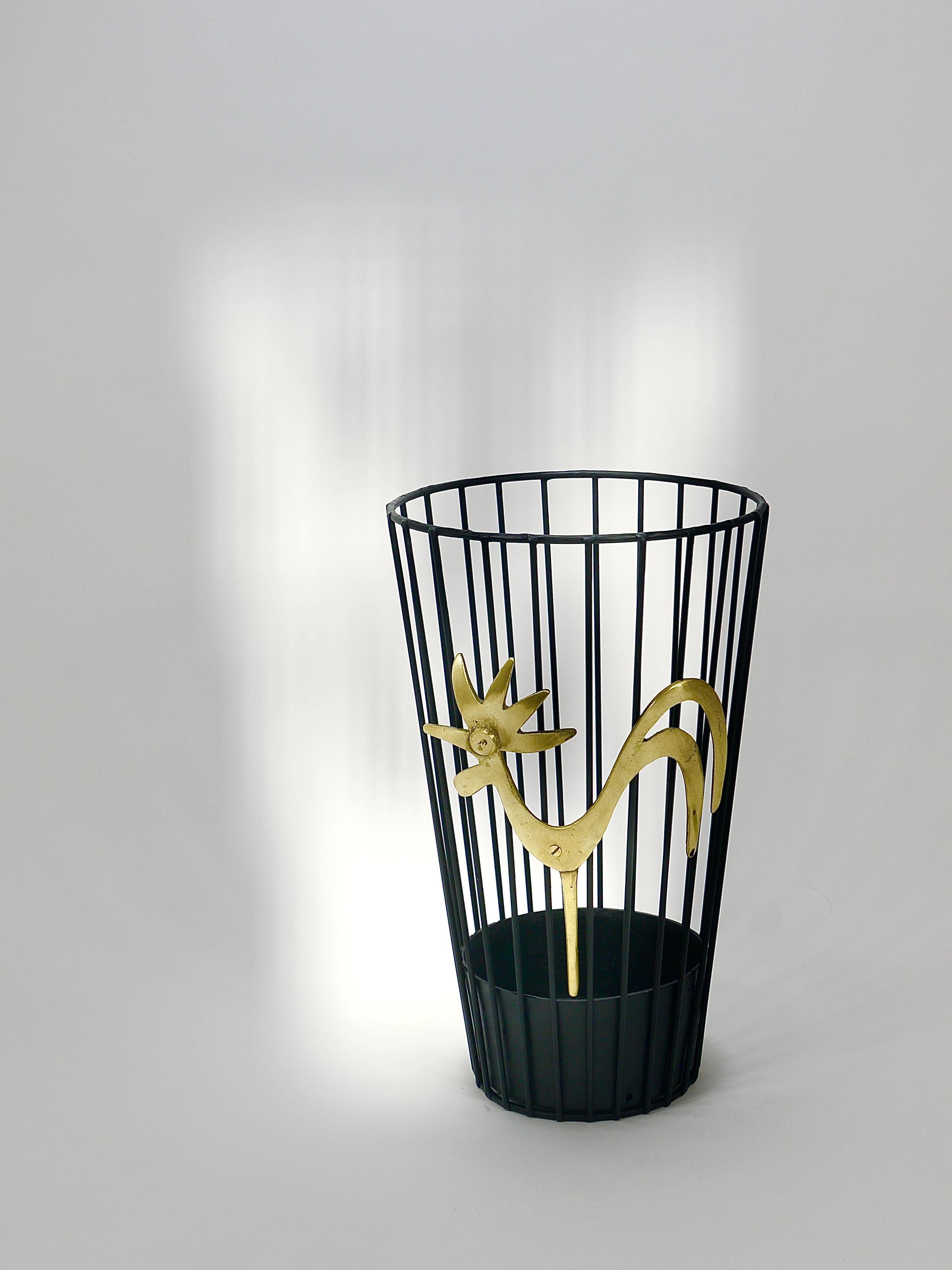 This striking umbrella stand, which can also serve as a paper basket or wastepaper bin, dates back to the 1950s. Designed by Walter Bosse and crafted by Hertha Baller in Vienna, Austria, it is made from metal with a black finish. The front is