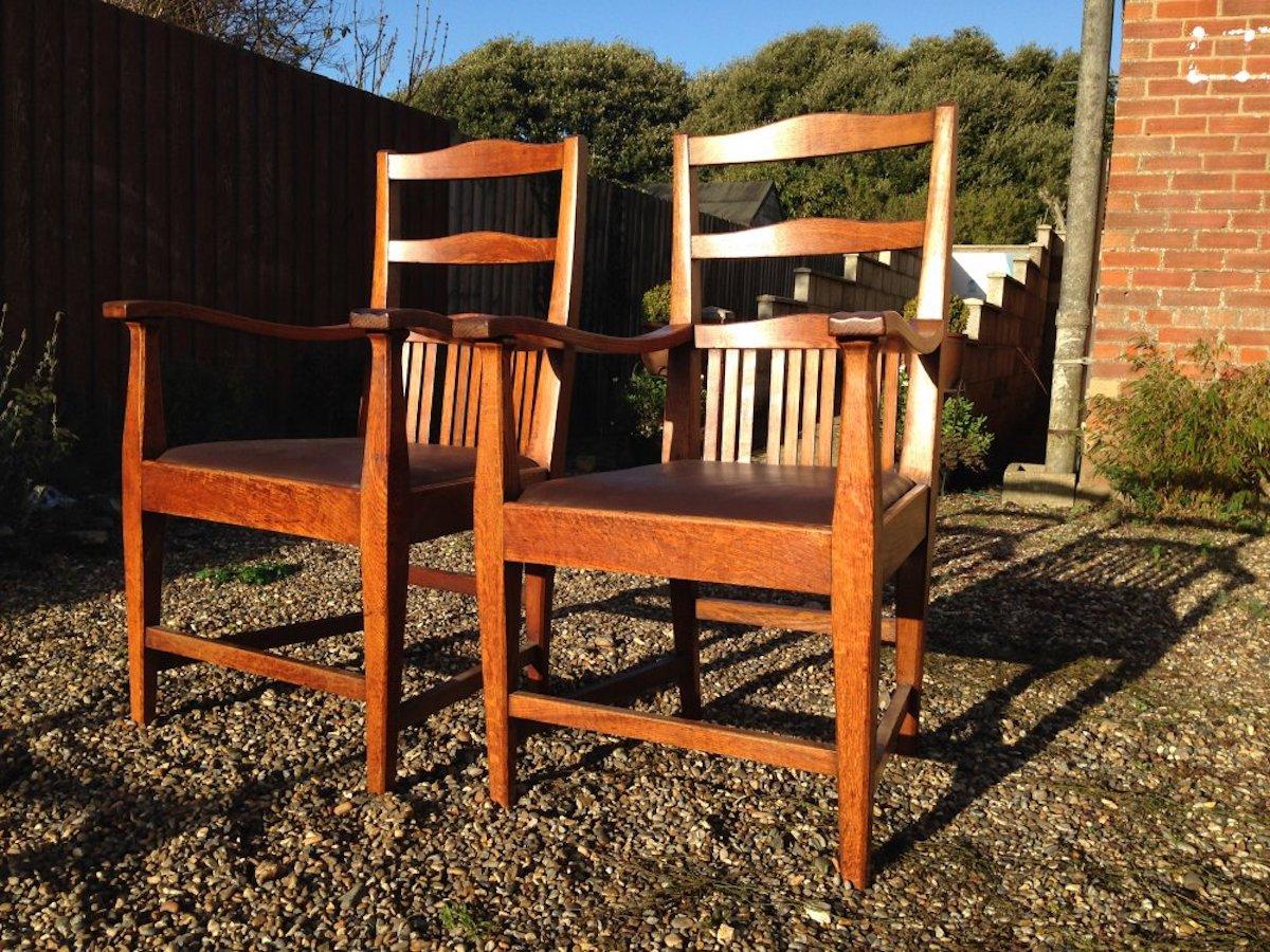 Walter Cave attributed. A comfy pair of Arts & Crafts oak armchairs with curvaceous backs and subtle carved details to the arms.