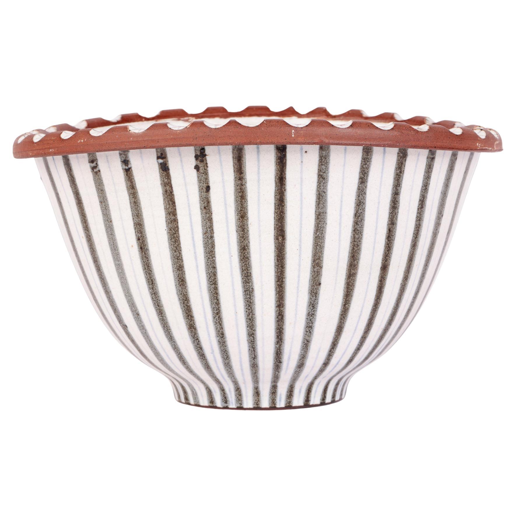 A stylish and large mid-century Rye studio pottery bowl decorated with linear patterning by Walter and Jack Cole. The bowl is of pinched oval shape standing on a narrow round foot with a fold over top edge. The bowl is finely potted and the body is