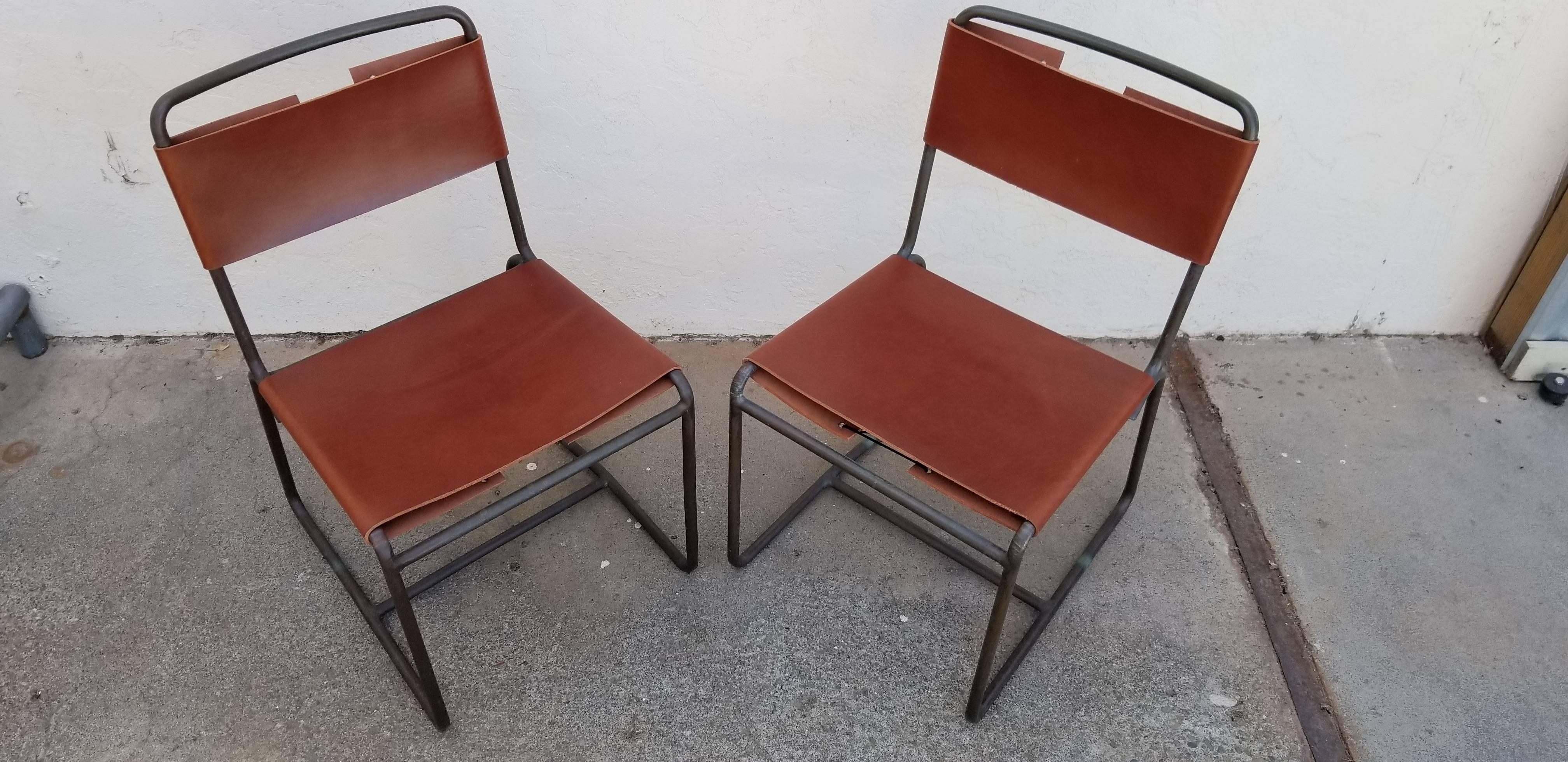 A pair of bronze and leather side or dining chairs by Walter Lamb. Unique and atypical sling style upholstery in hide leather with adjustable riveted ties. Beautiful patina to bronze frames.