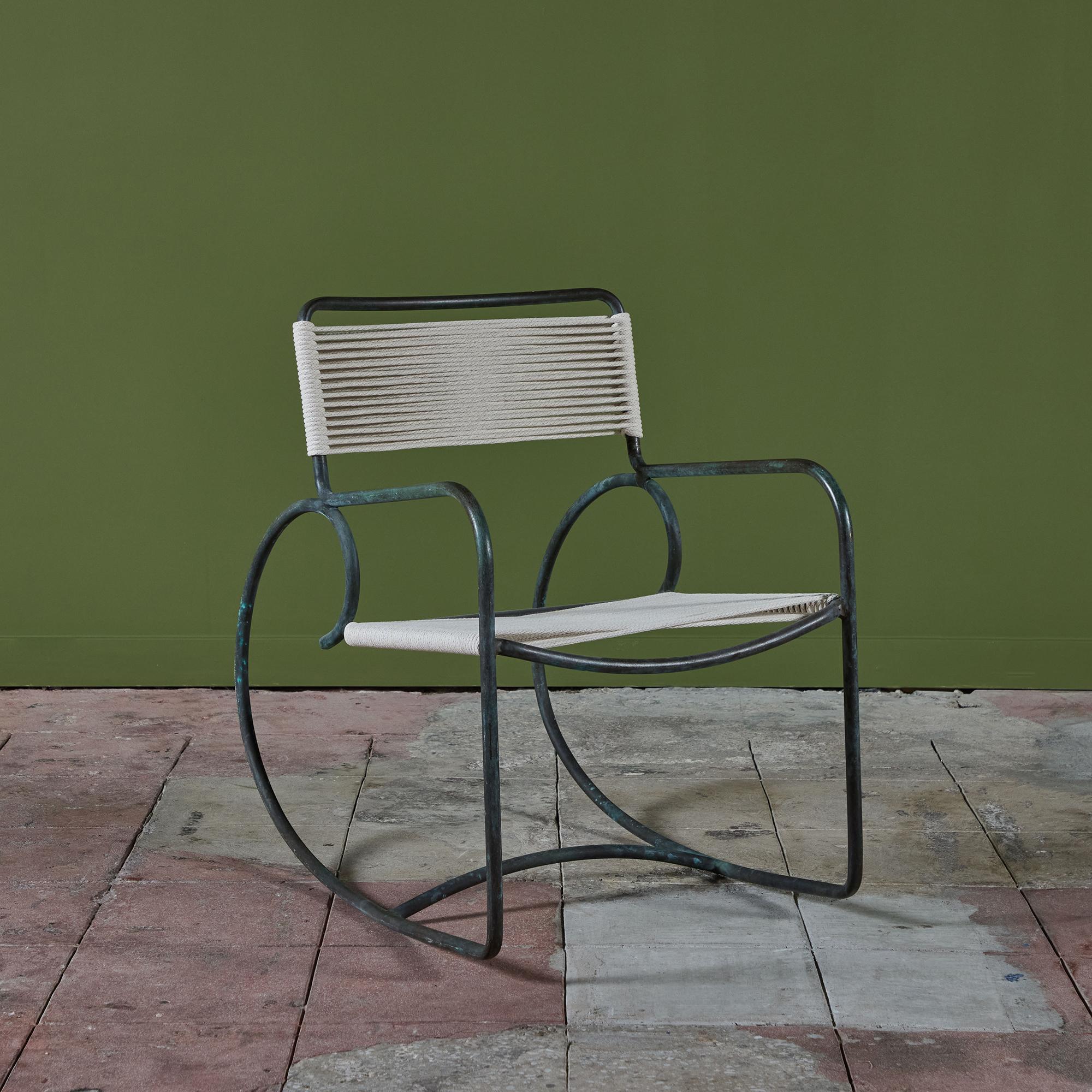 Ein Schaukelstuhl aus Bronze, entworfen von Walter Lamb und hergestellt von Brown Jordan. Der Stuhl hat eine skulpturale Form, mit einer einzigen Formation aus Bronzerohr, die die Rückenlehne, die Armlehnen und die übertrieben runden Kufen bildet,