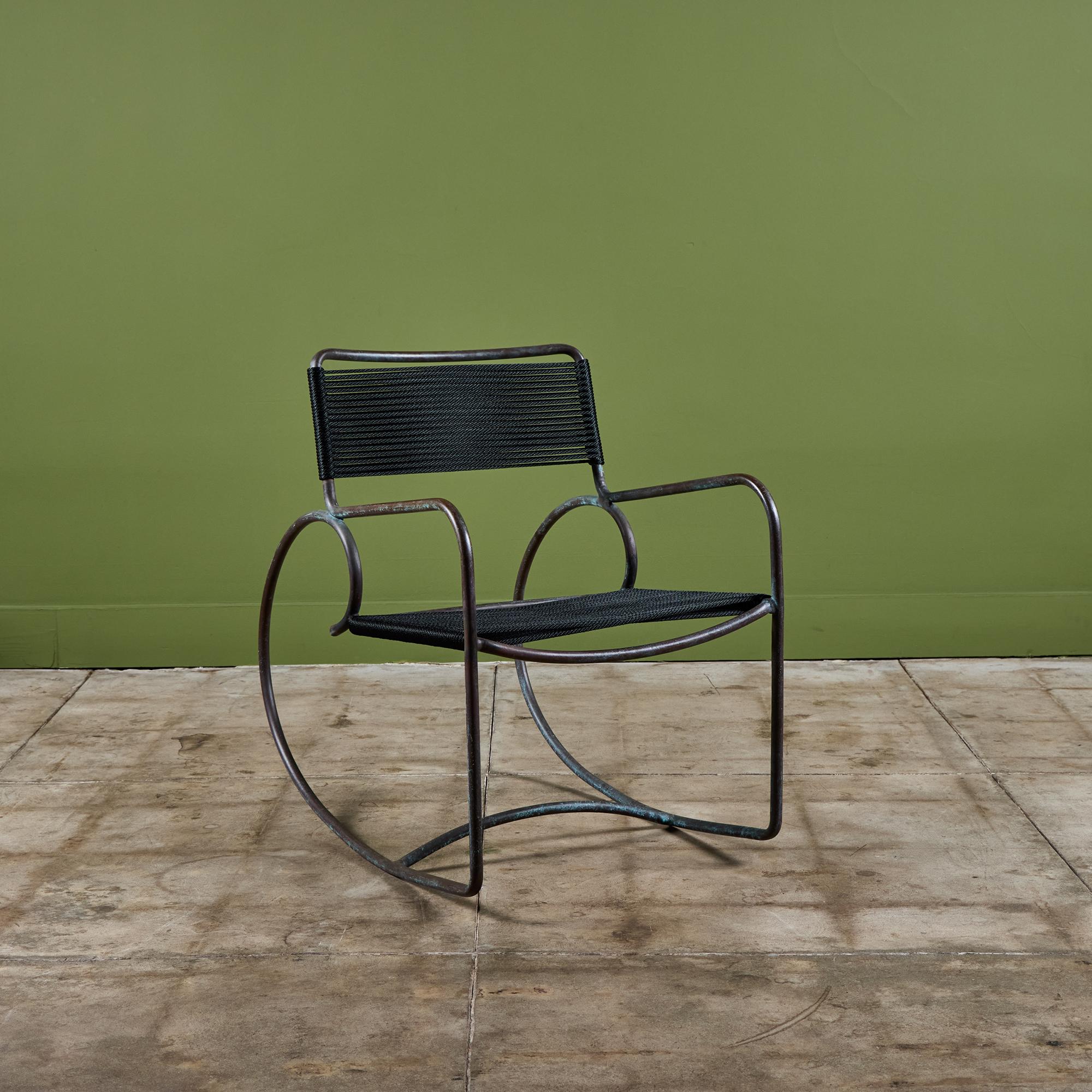 A bronze rocking chair designed by Walter Lamb and produced by Brown Jordan. The chair has a sculptural shape, with a single formation of tubular bronze forming the backrest, arms, exaggerated round runners, with a stylistic curlicue at each end.