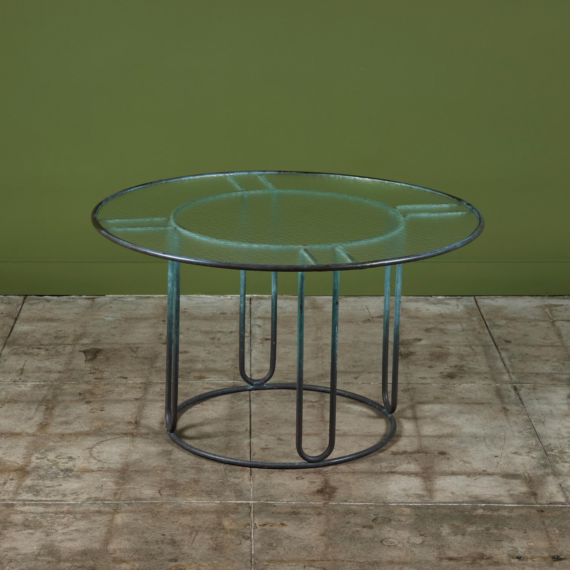 Ein Esstisch für die Terrasse aus patinierter Bronze, entworfen von Walter Lamb und hergestellt von Brown Jordan. Der runde Rahmen besteht aus zwei konzentrischen Bronzeringen mit radialen Stützen und einem runden Bronzesockel. Die runde Tischplatte