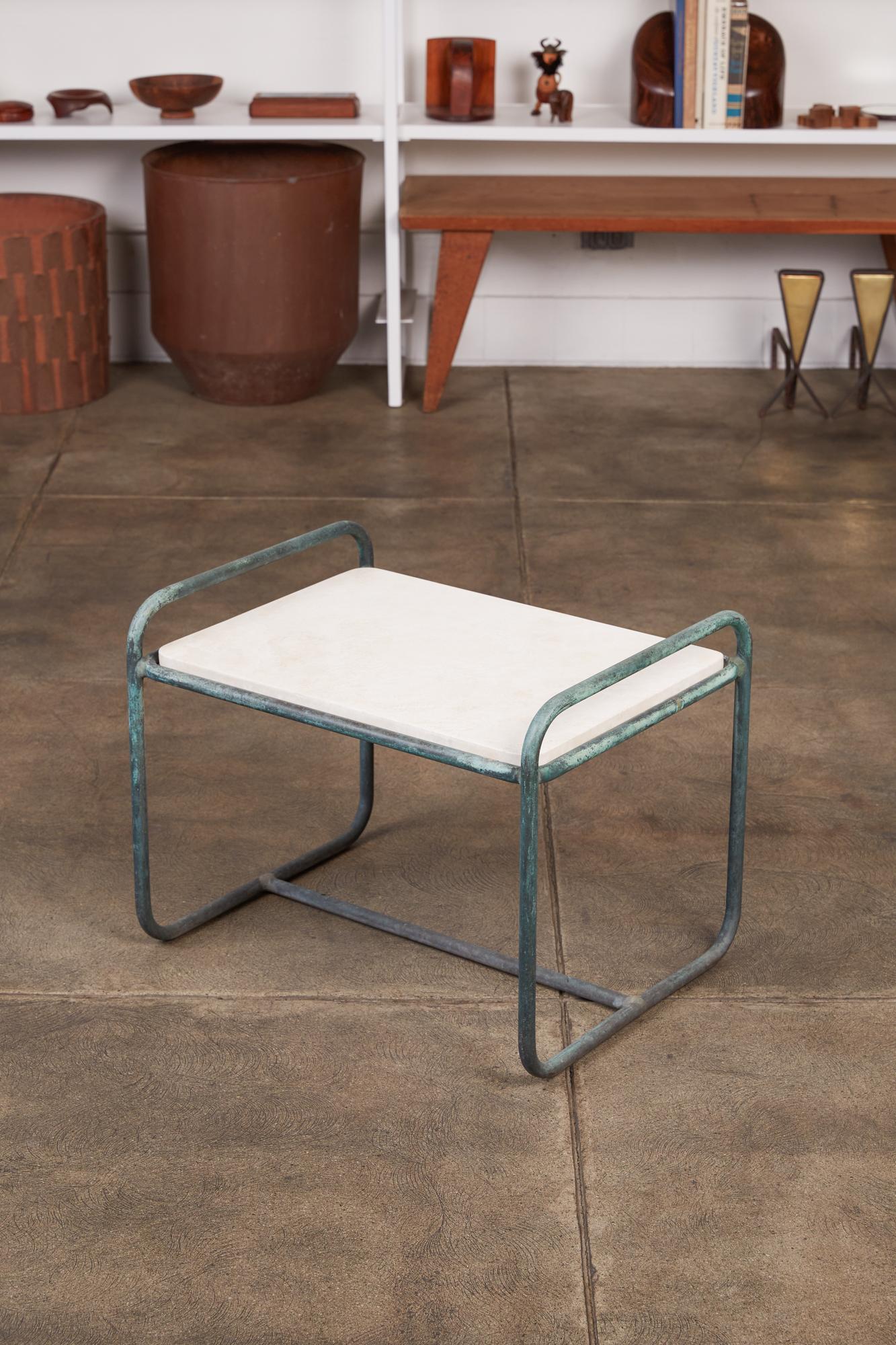 Patio side table designed by Walter Lamb and produced by Brown Jordan. The table frame is bronze tubing with a verdigris patina with new travertine top. Two curved rails form the legs and create the “handles” on either side of the table