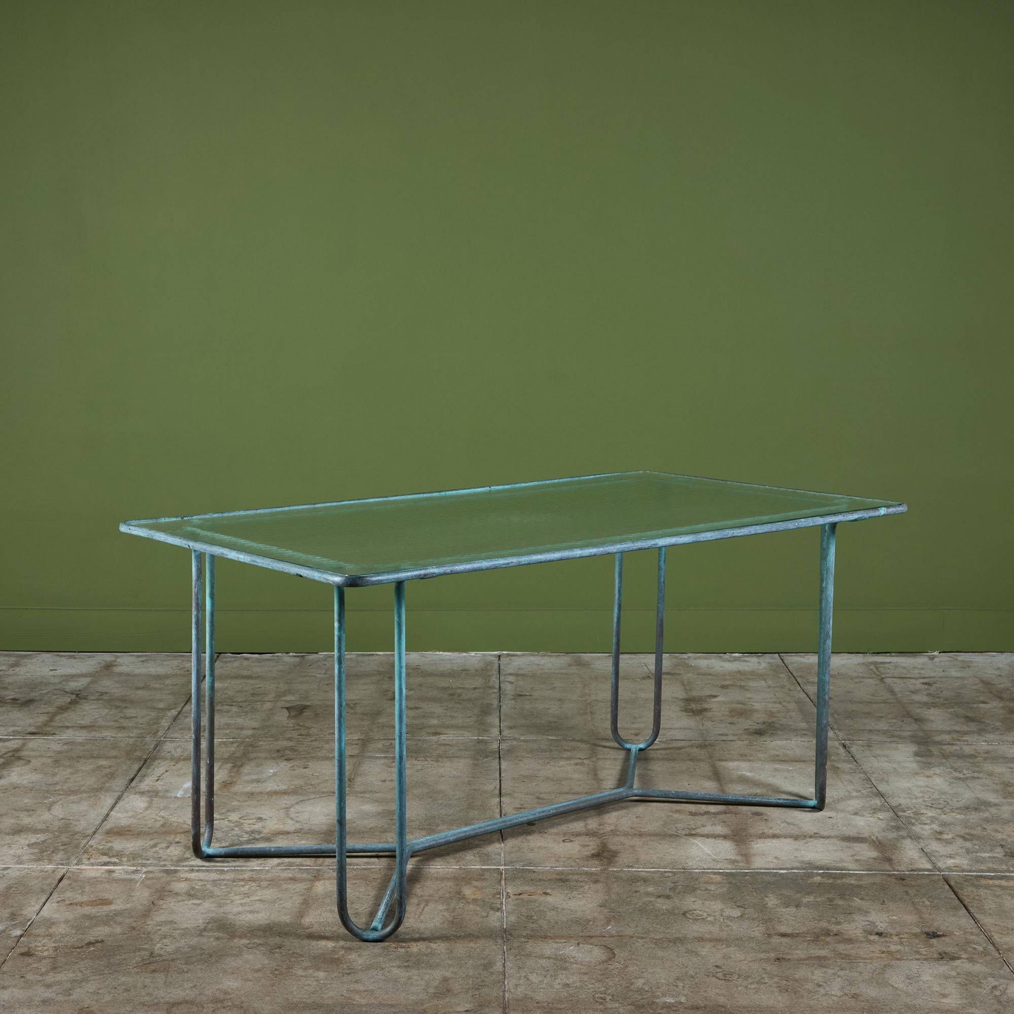 Table de salle à manger en bronze patiné conçue par Walter Design/One et produite par Brown Jordan. La table a une forme rectangulaire avec des coins arrondis, soutenue par quatre pieds en épingle à cheveux en bronze assorti. Les pattes sont reliées