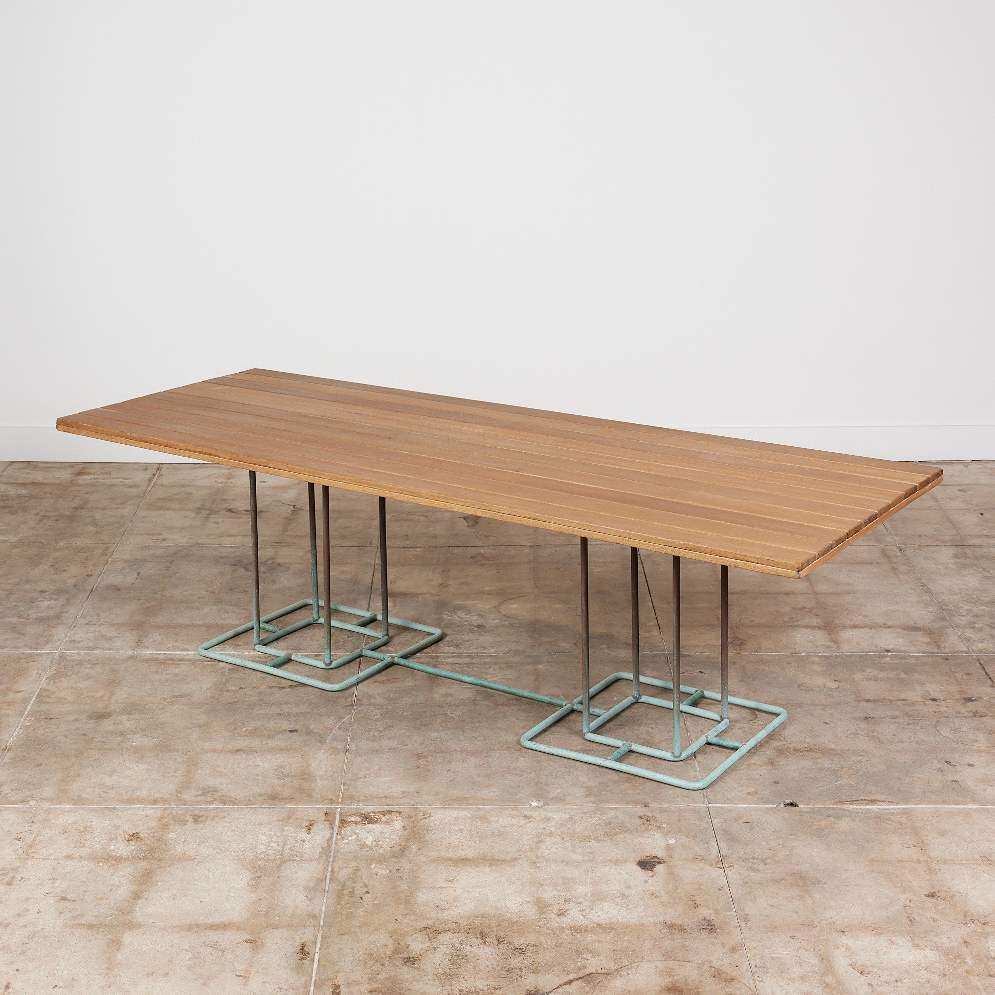 An impressive eight foot rectangular patio table designed by Walter Lamb and manufactured by Brown Jordan. The table has a slatted surface in the original weathered wood, mounted on a double bronze base. Its subtle geometry suggests an Arts & Crafts