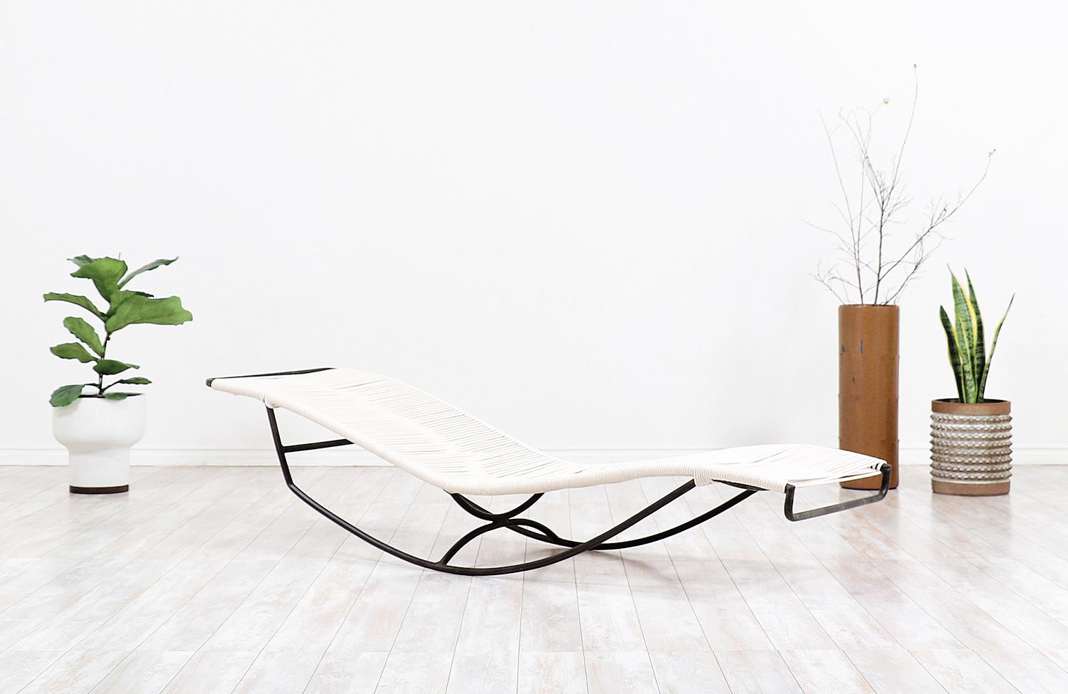 Chaise lounge designed by Walter Lamb for Brown Jordan in the United States c. 1950’s. Known for his outdoor furniture designs, Lamb’s “Waikiki” rocking chaise lounge chair features a tubular bronze frame and has been newly re-strung with flag