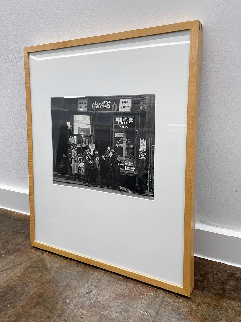 Chick's Candy Store, Pitt St. N.Y. von Walter Rosenblum ist eine Schwarz-Weiß-Fotografie, die eine Gruppe von Menschen zeigt, die sich vor einem Geschäft in einer Straße in New York City versammelt haben.

Gelatinesilberdruck
10,5 x 13,5