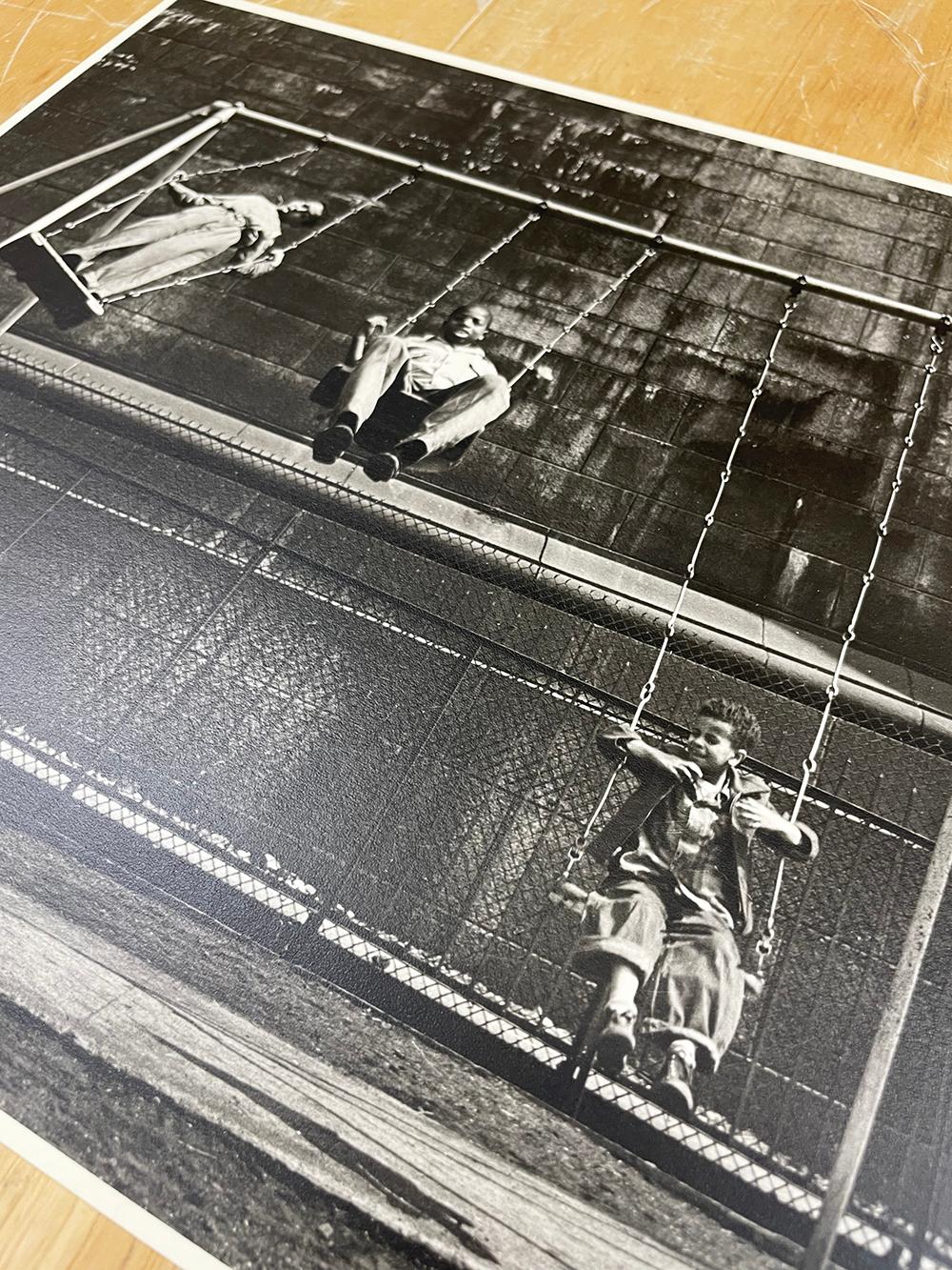 Three Boys on a Swing, Pitt St. N.Y. von Walter Rosenblum ist eine Schwarzweißfotografie, die drei Kinder beim Spielen auf einer Schaukel in einem Stadtpark zeigt.

Gelatinesilberdruck
10,5 x 13,5 Zoll.
Verso signiert, betitelt und datiert in Tinte