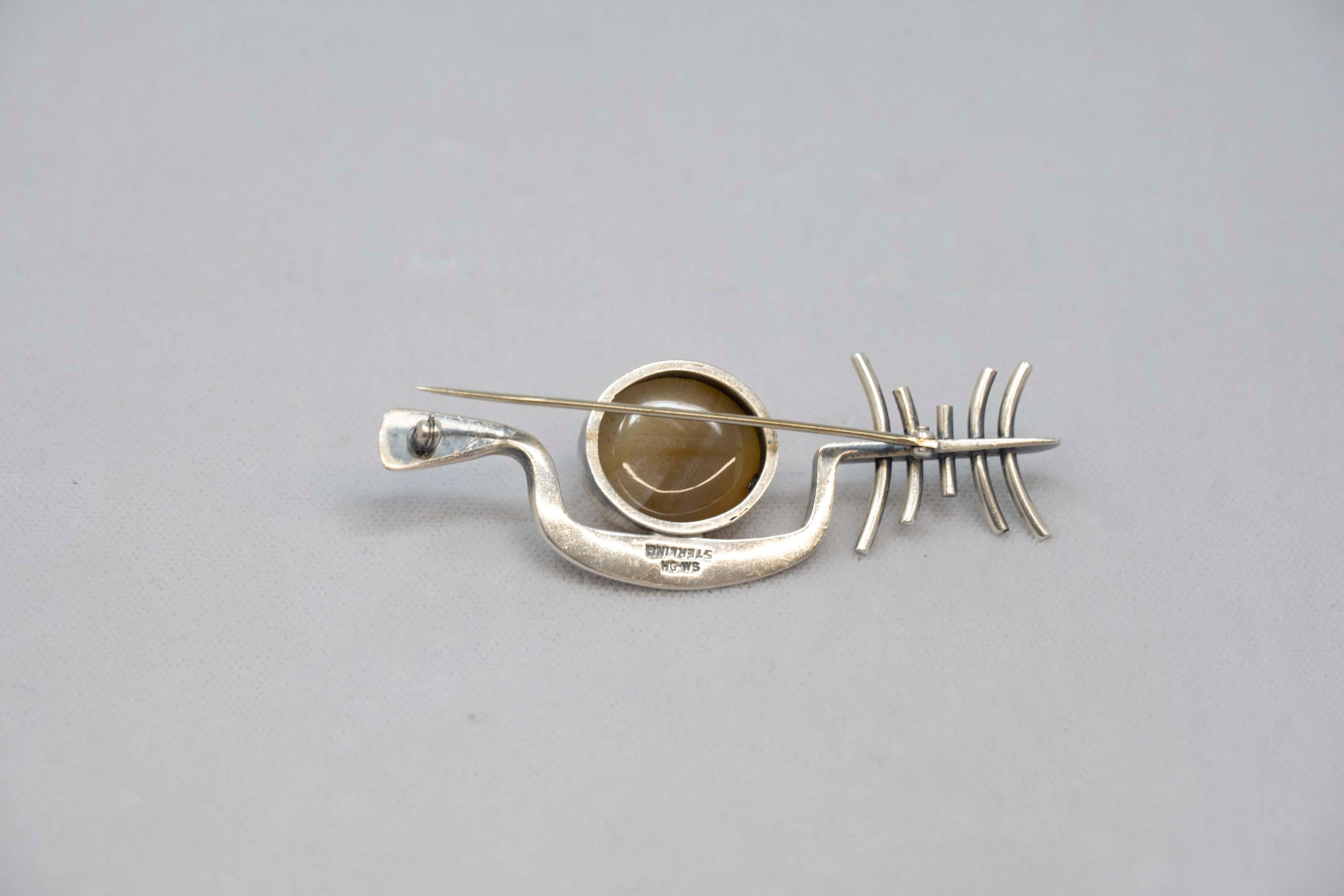 Sterling brooch modernist design with a 20 x 17 mm, agate semi precious stone, circa 1980. Signed HG-WS sterling, brooch measures 3 inches long. In good condition.
