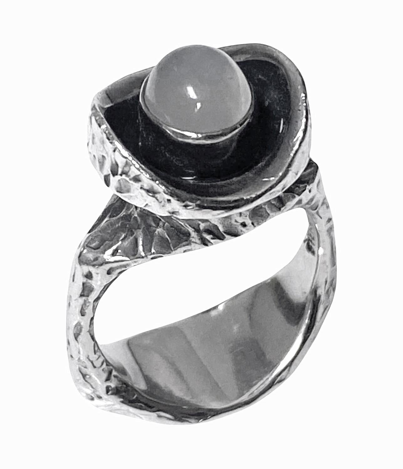 Walter Schluep Skulpturaler handgefertigter Ring aus Sterlingsilber, C.1970. Die konkave Oberseite ist oxidiert und mit einem Mondstein besetzt, die umlaufende Fassung ist mit einer rindenähnlichen Textur versehen. Oberkante ca. 14,70 mm. Ring Größe