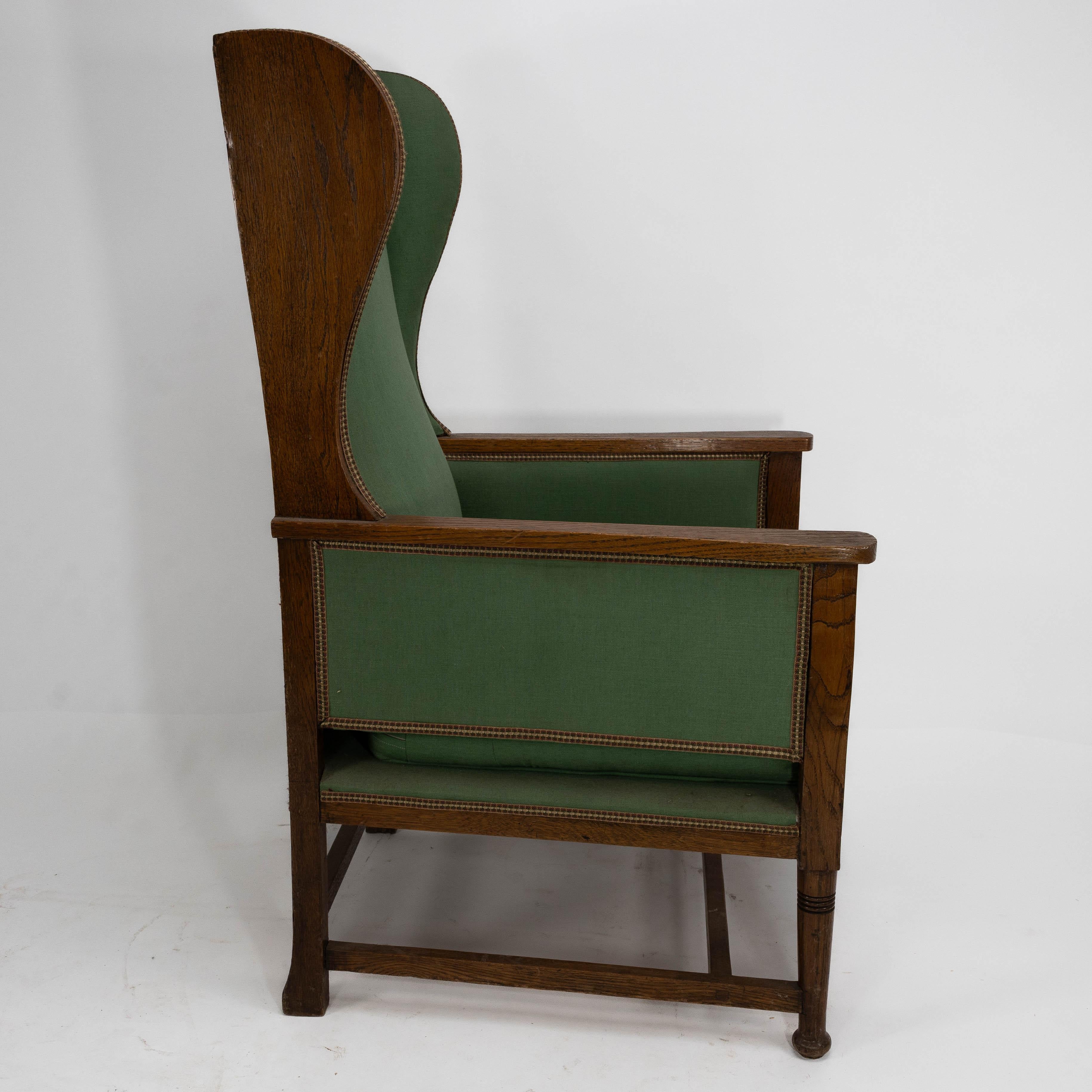 English Walter Skull High Wycombe. An Arts and Crafts oak wing back upholstered armchair For Sale